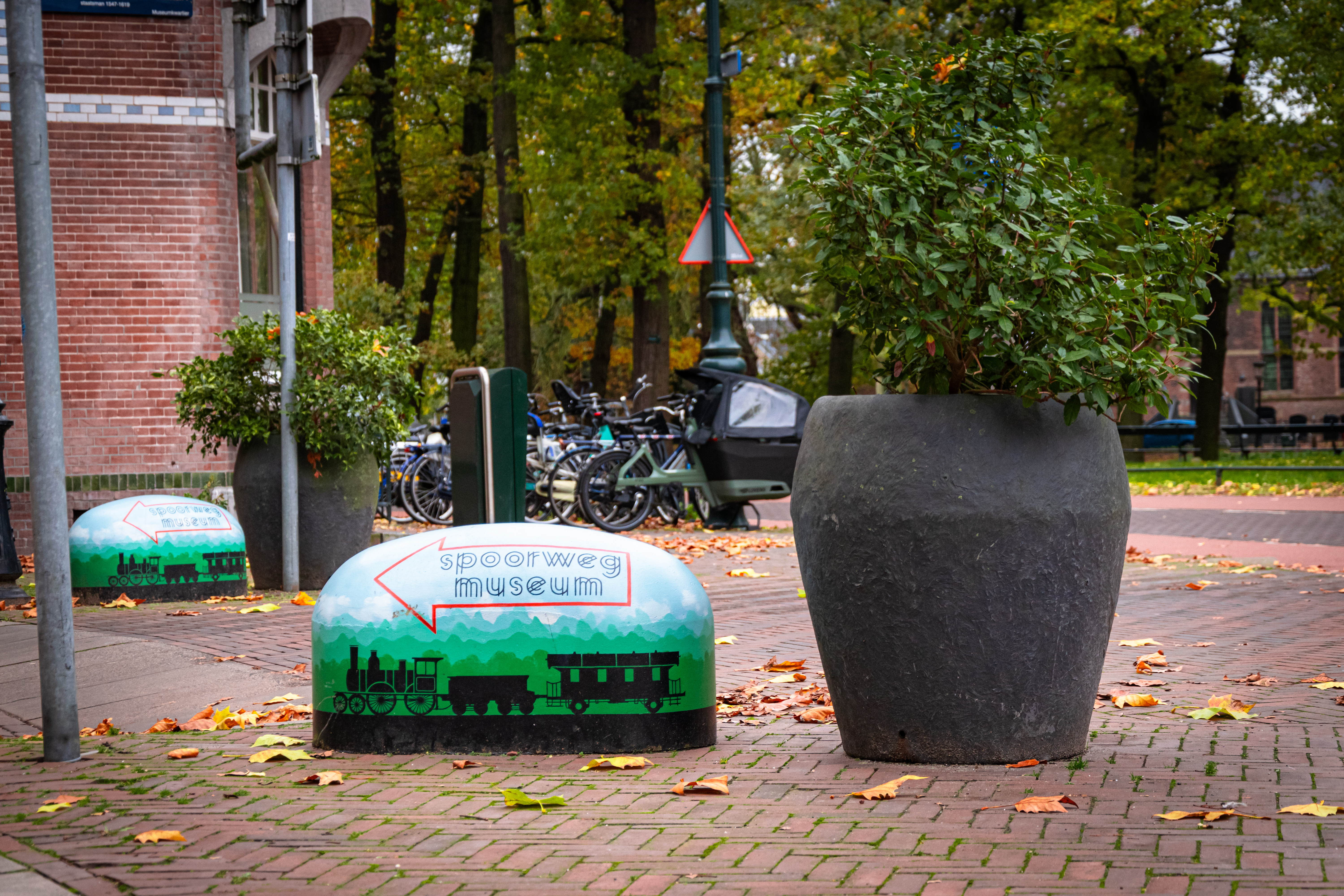 a stone directing towards a railway museum and a pot with a flower thing