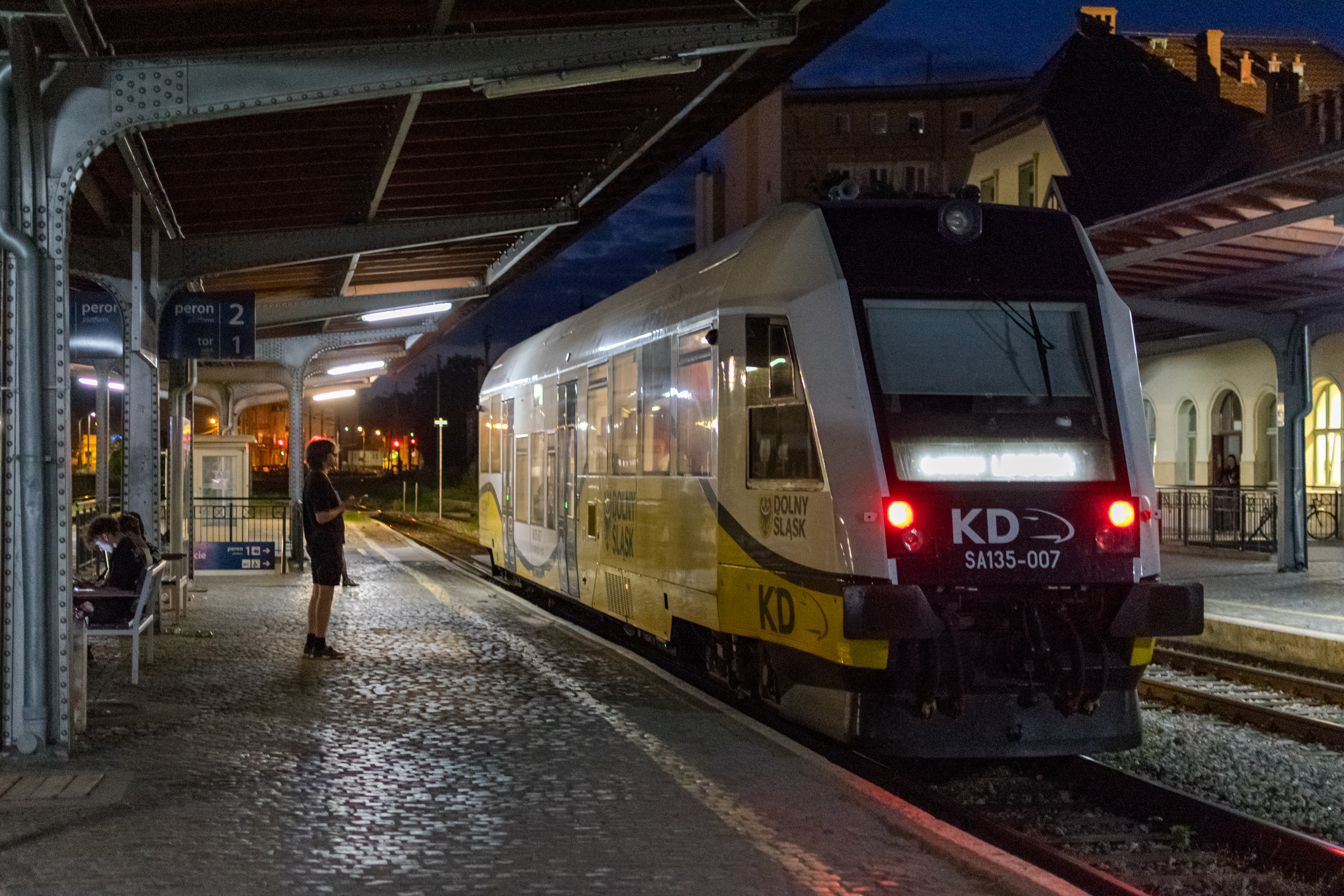 yellow-white train stopped at a platform at night