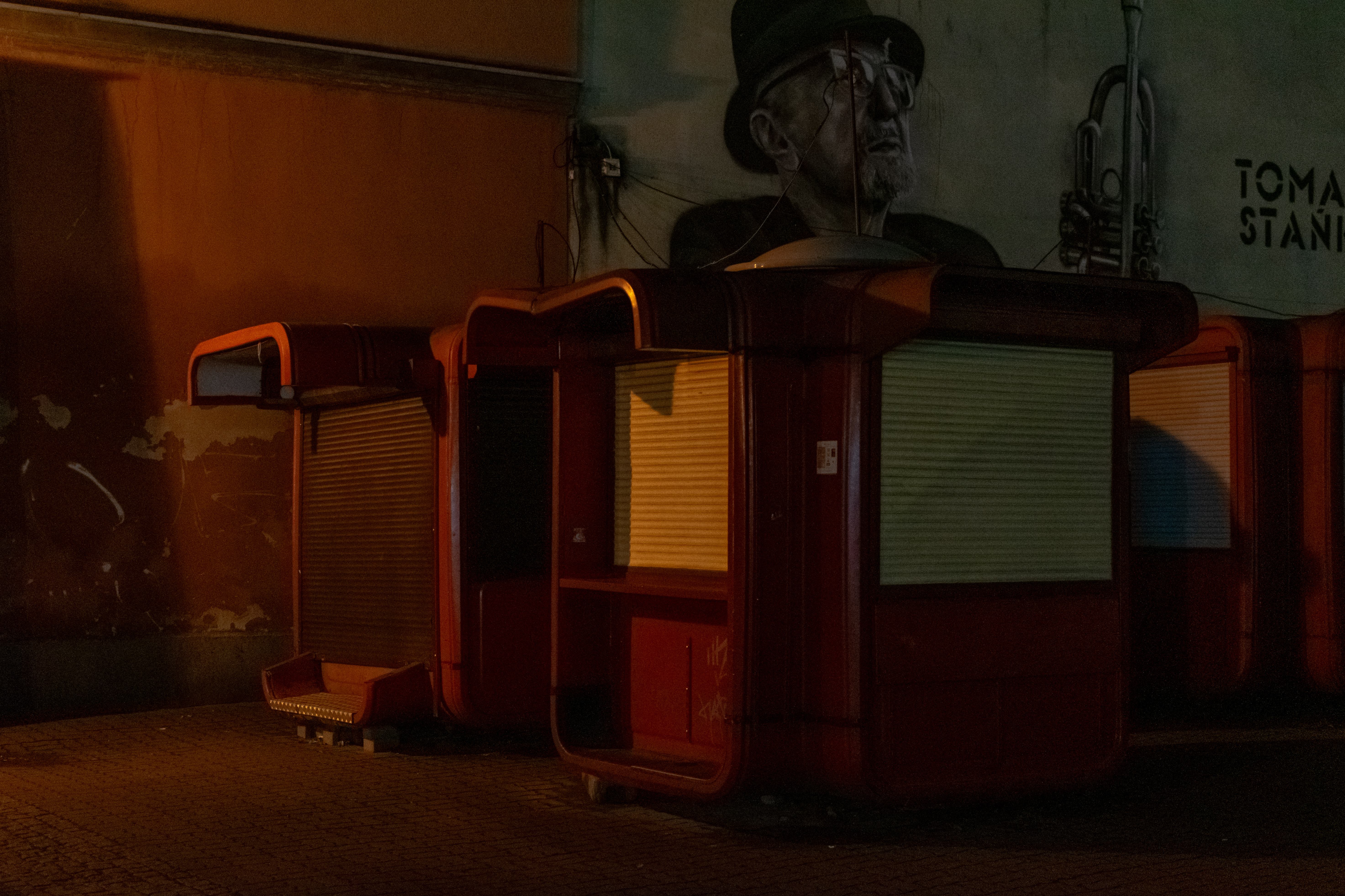 old red kiosk-style things from 90s, barely illuminated by street lights