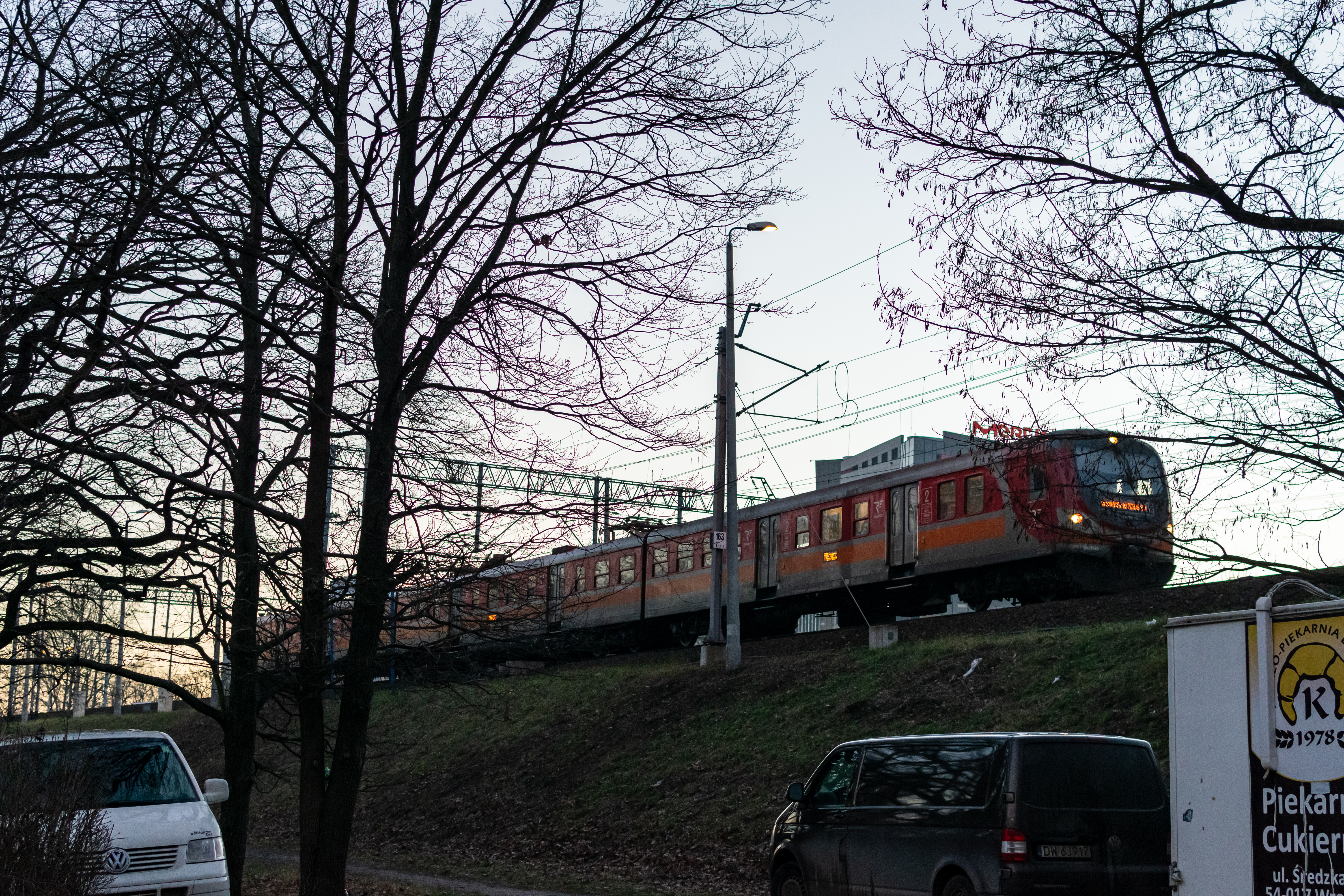 orange-red EN57 arriving at the station, visible from outside of the station