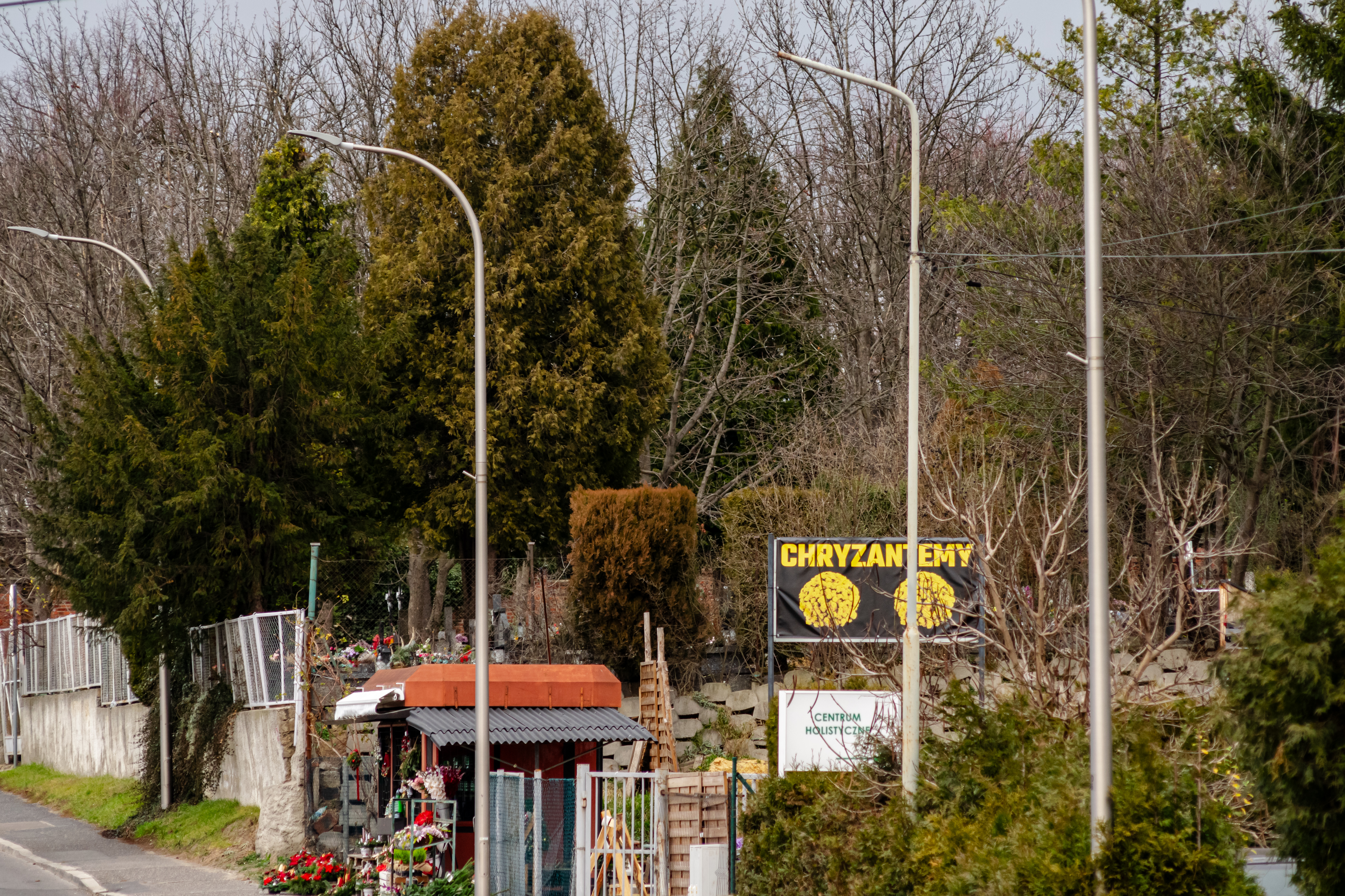 a kiosk with flowers, with a banner advertising it, next to a cemetery