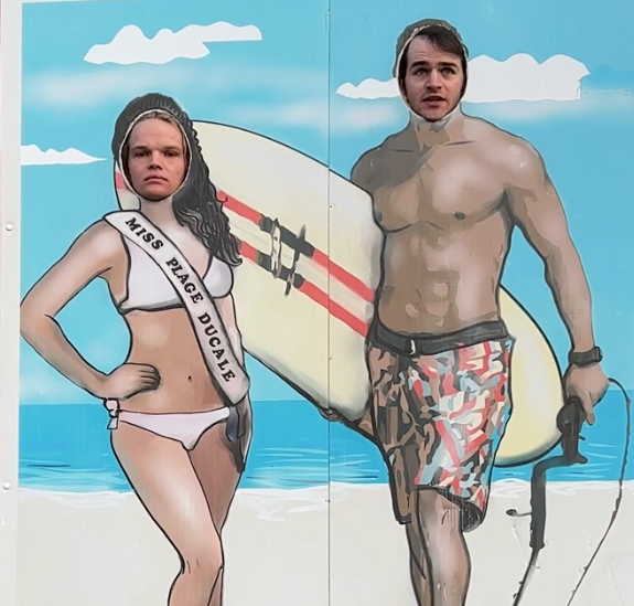 sam and adam from jet lag in one of those head cutout images on the street (where they can put their faces) in beach theme