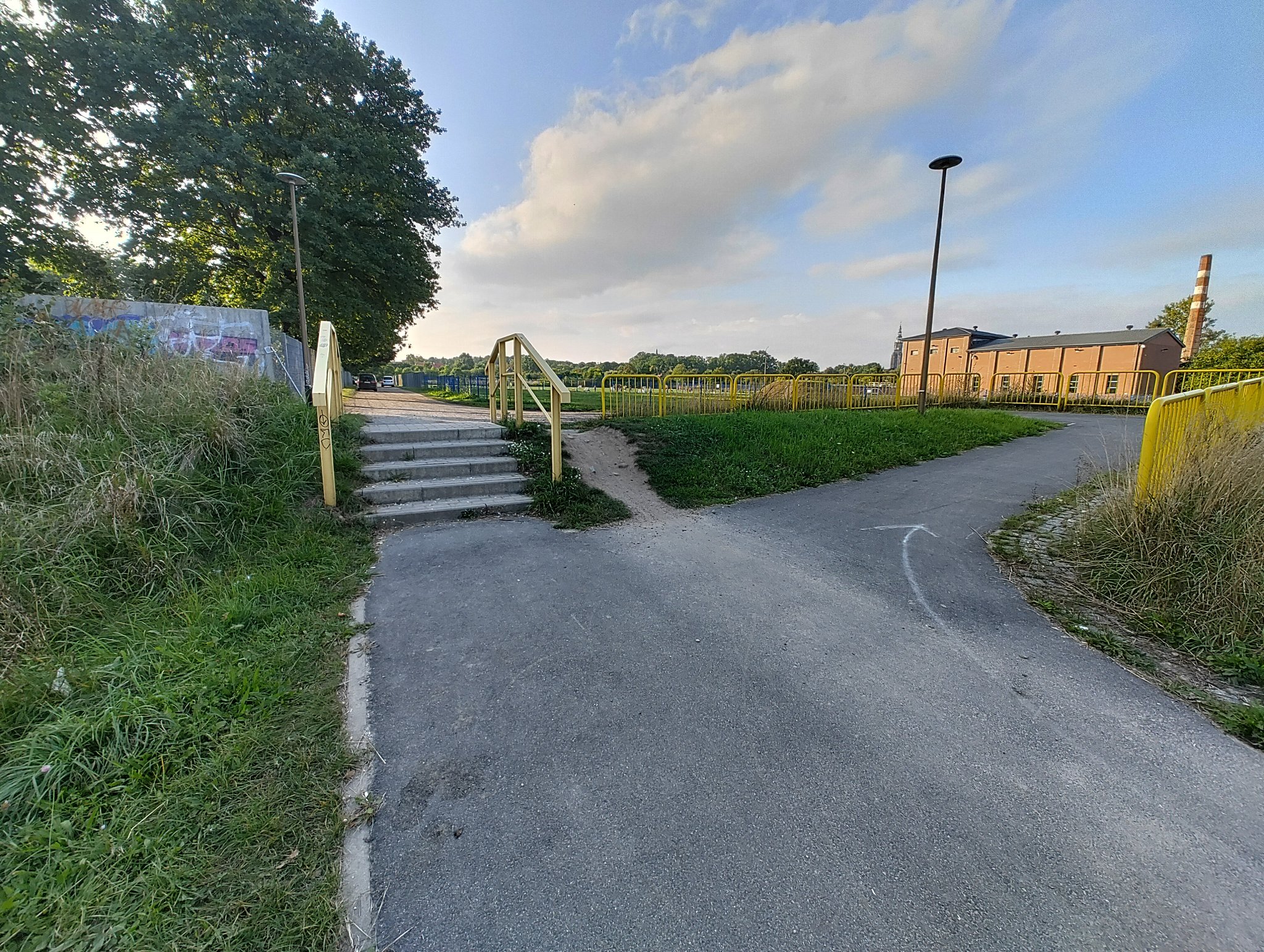 photo of the same structure but from other side, ramp is more visible, and stairs going down, alongside a said desire path that will probably flatten this out at some point
