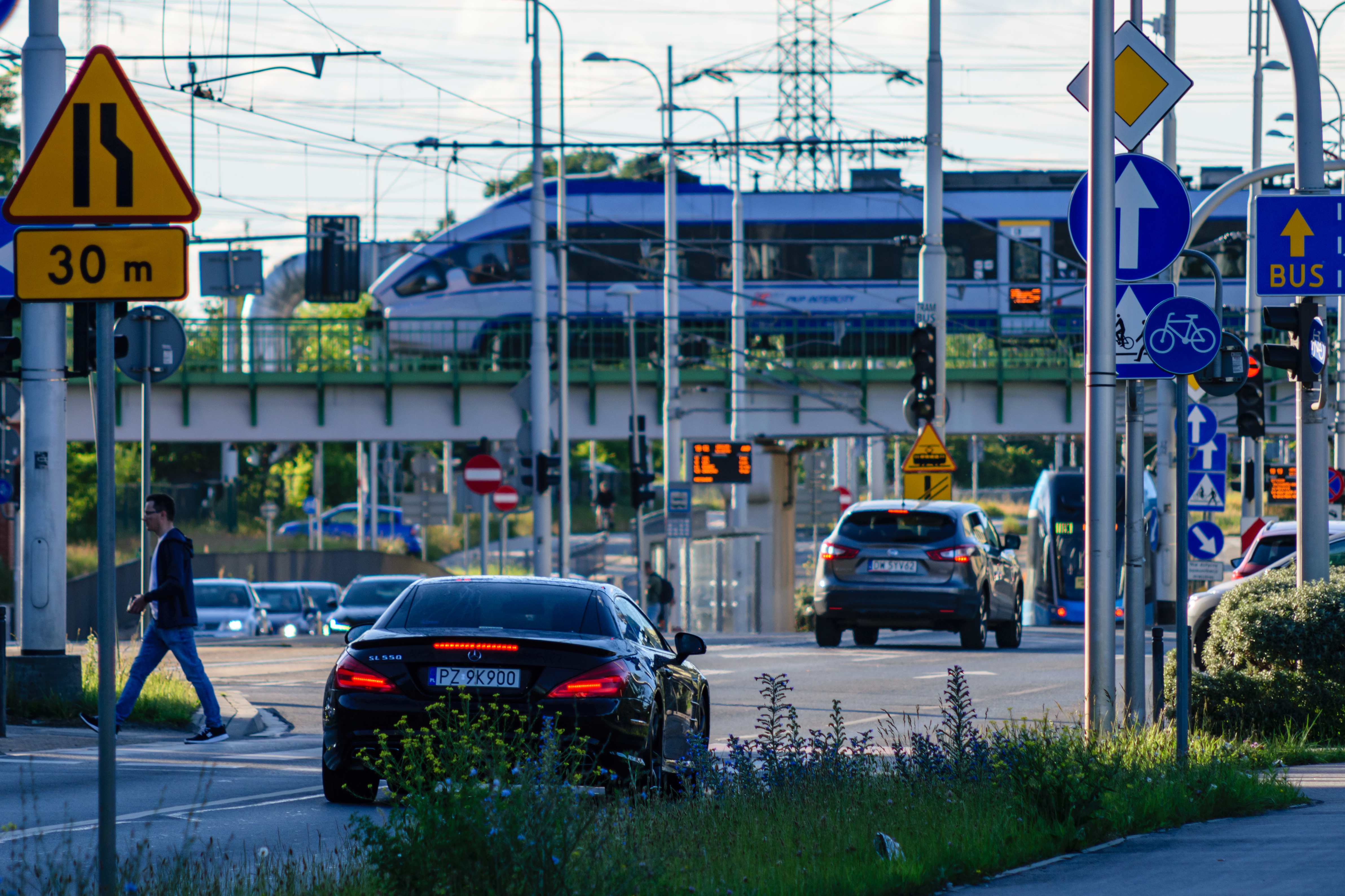 Expensive car waiting at traffic lights, there’s a train going by on viaduct
