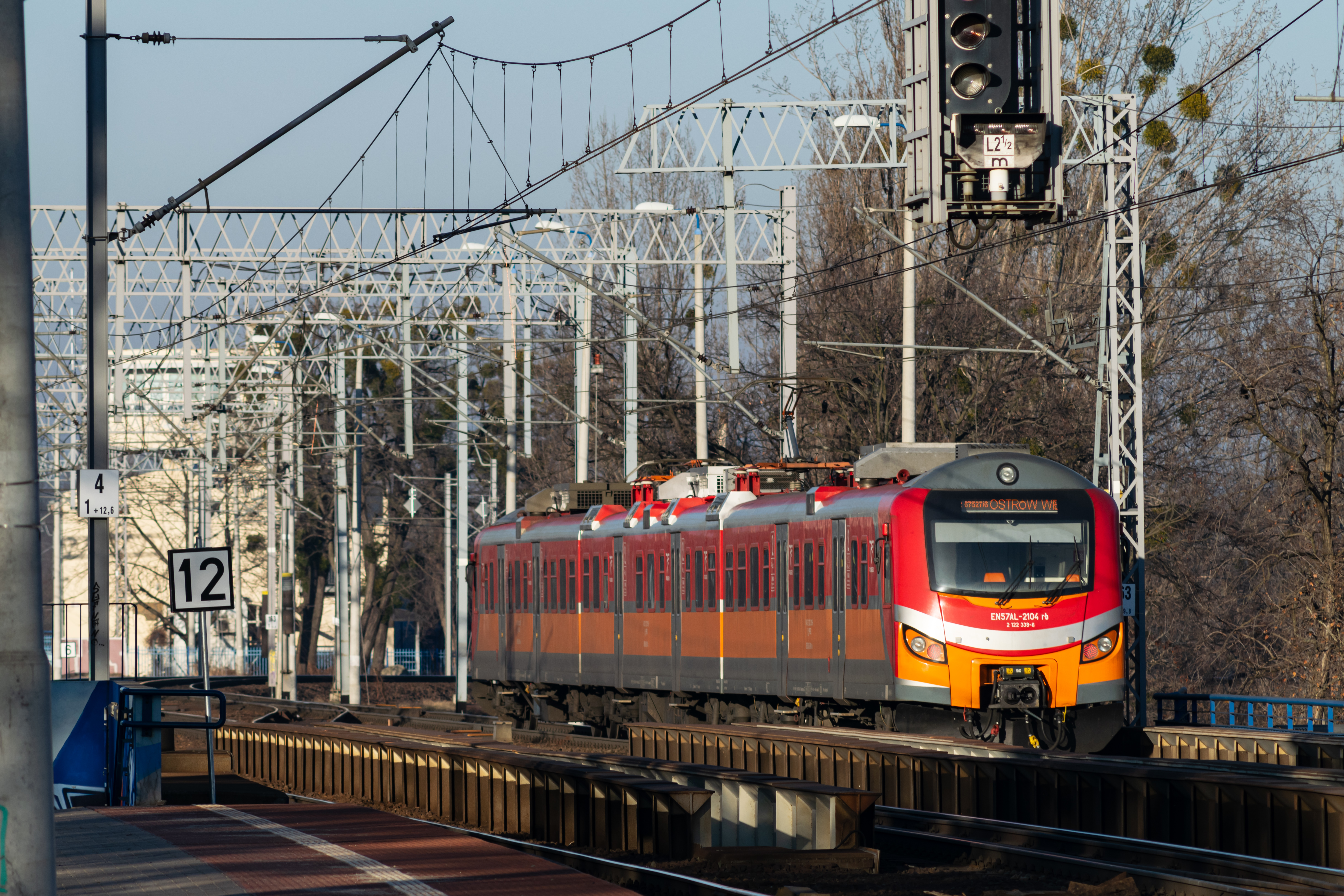 red-orange EN57AL leaving the station