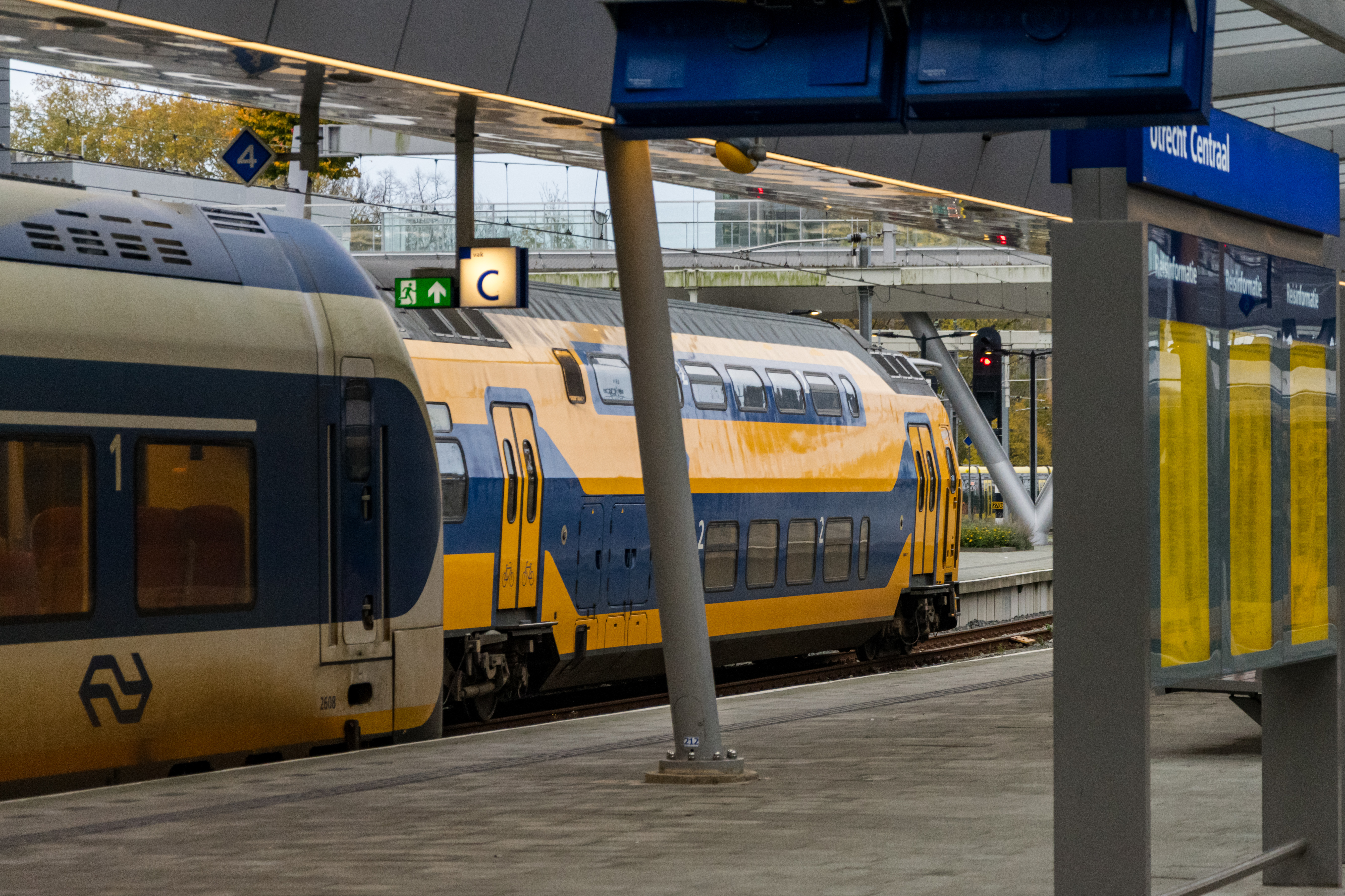 white-blue and yellow-blue trains at a station