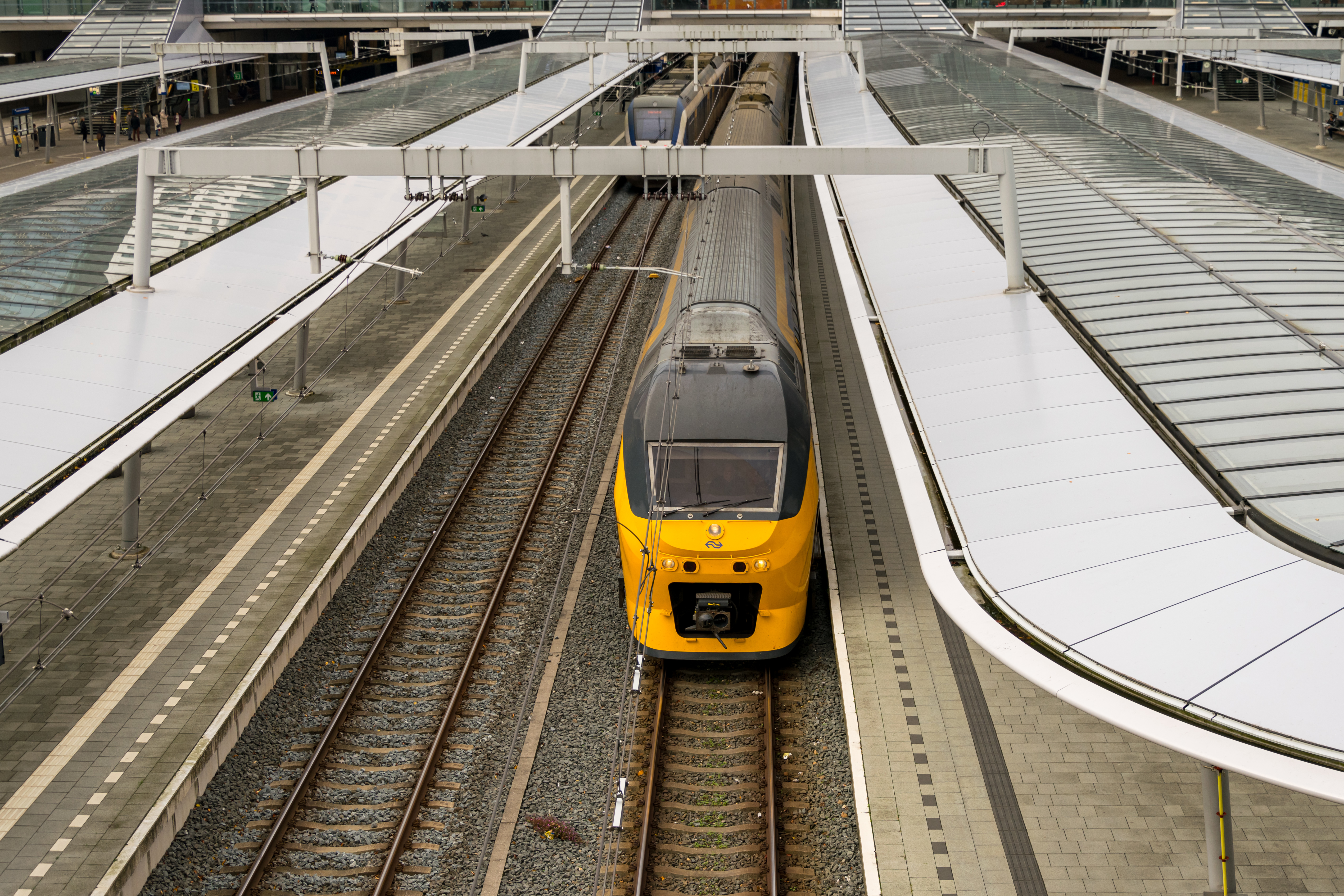yellow train at a platform viewed from a bridge