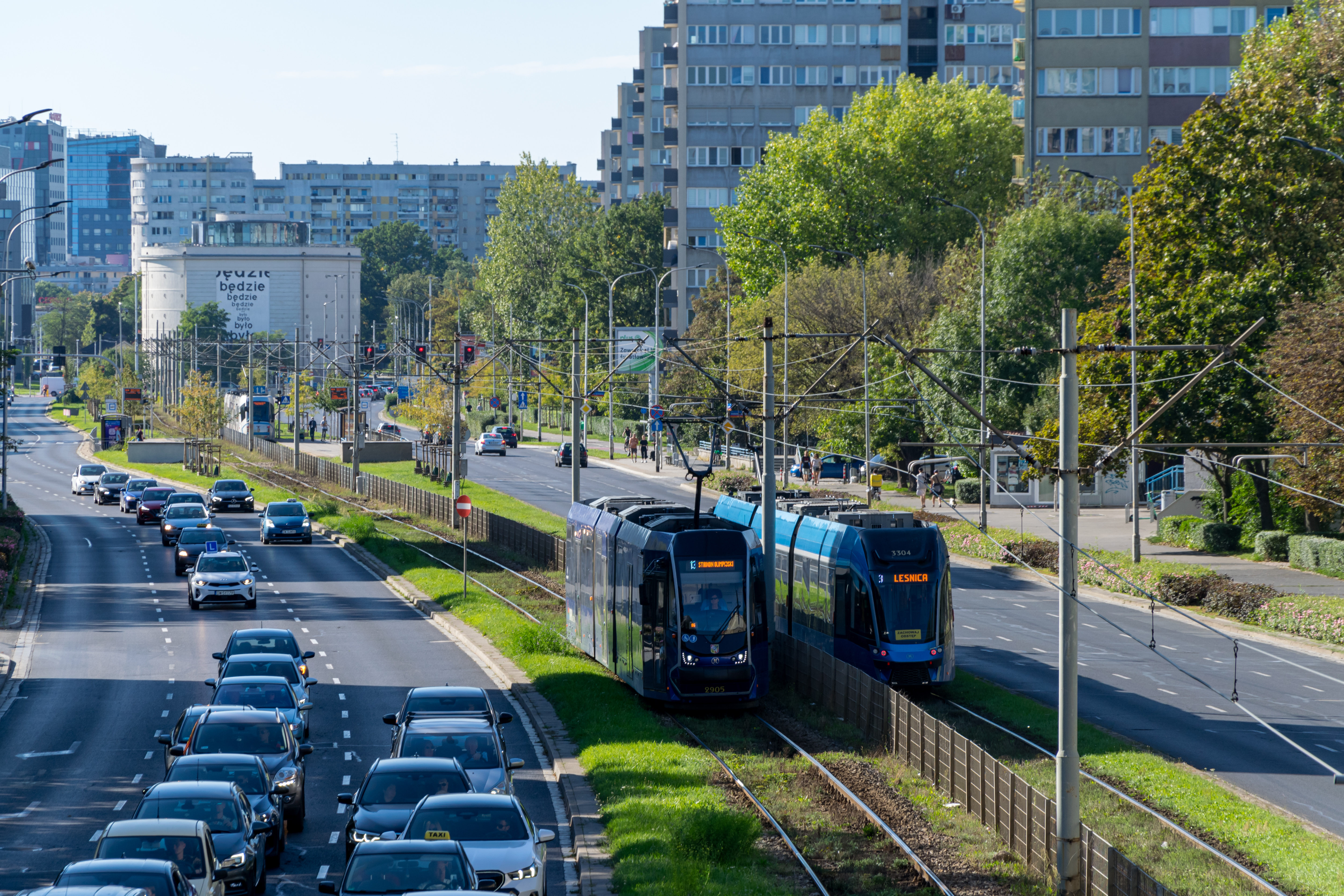 blue and dark-blue trams going past each other, there are multiple commie blocks in background