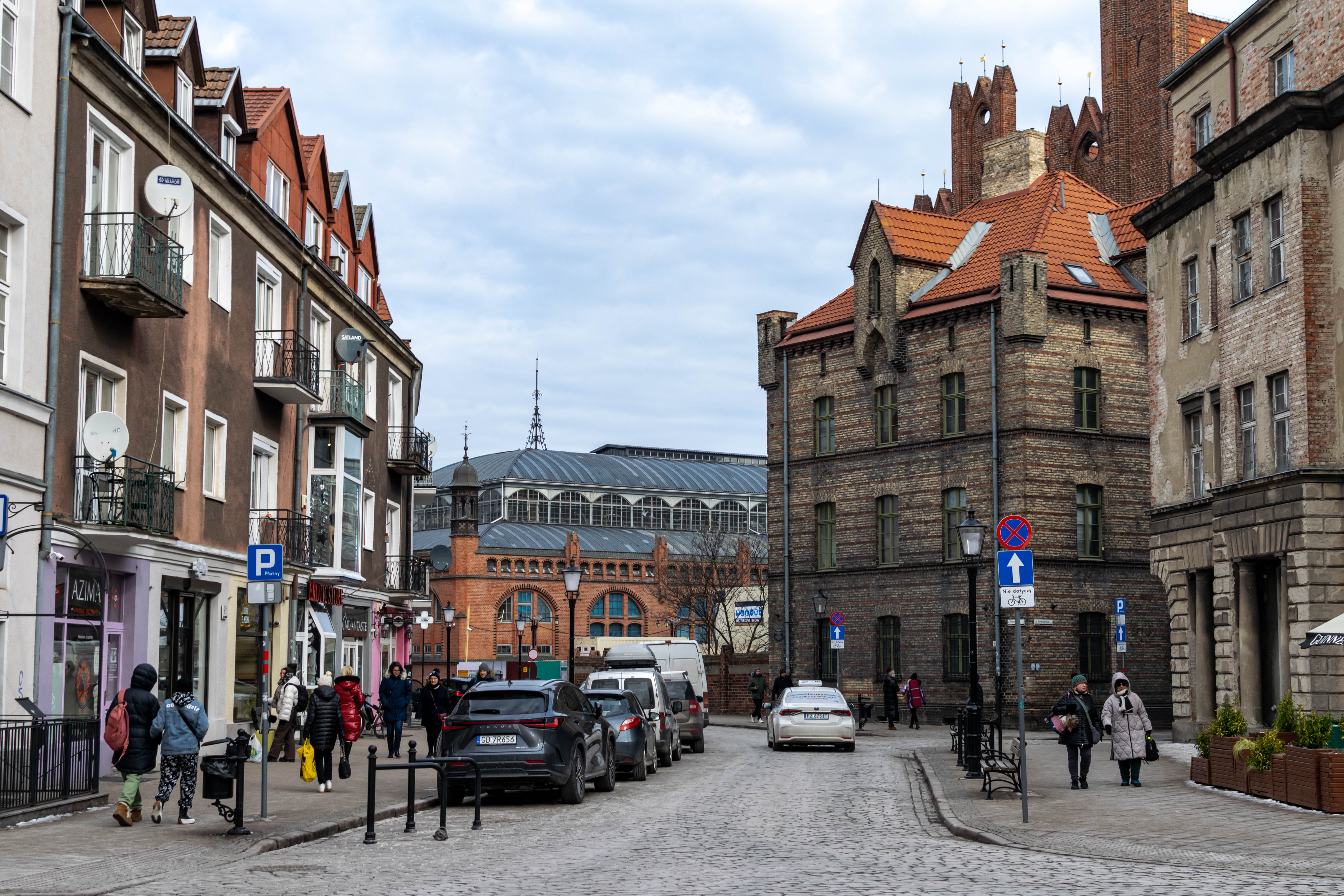 street with some brick buildings and a market hall in the background