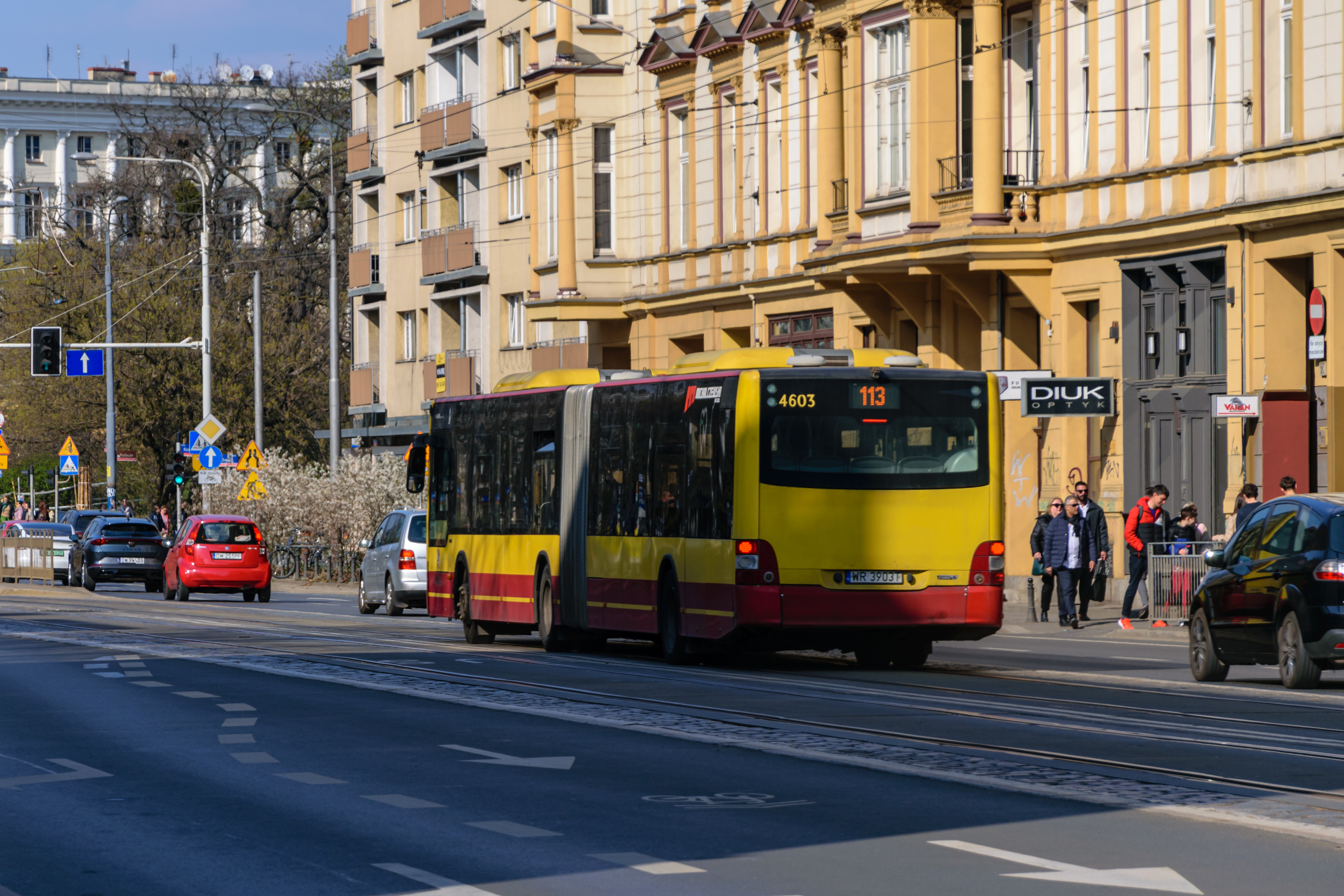 Back of the yellow-red bus getting closer to traffic lights