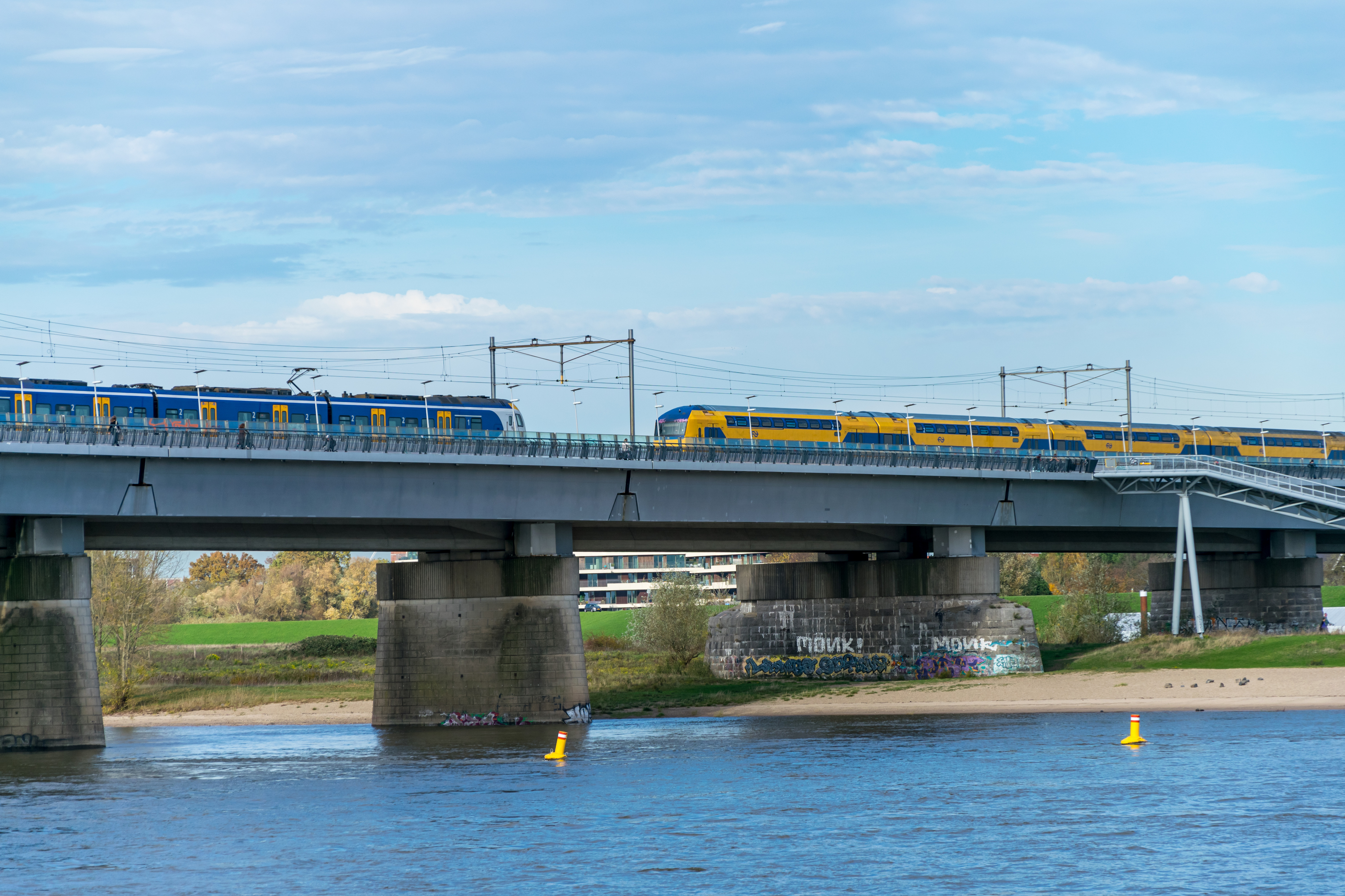 Yellow-blue double decker train and a blue-white-yellow regional train on a bridge