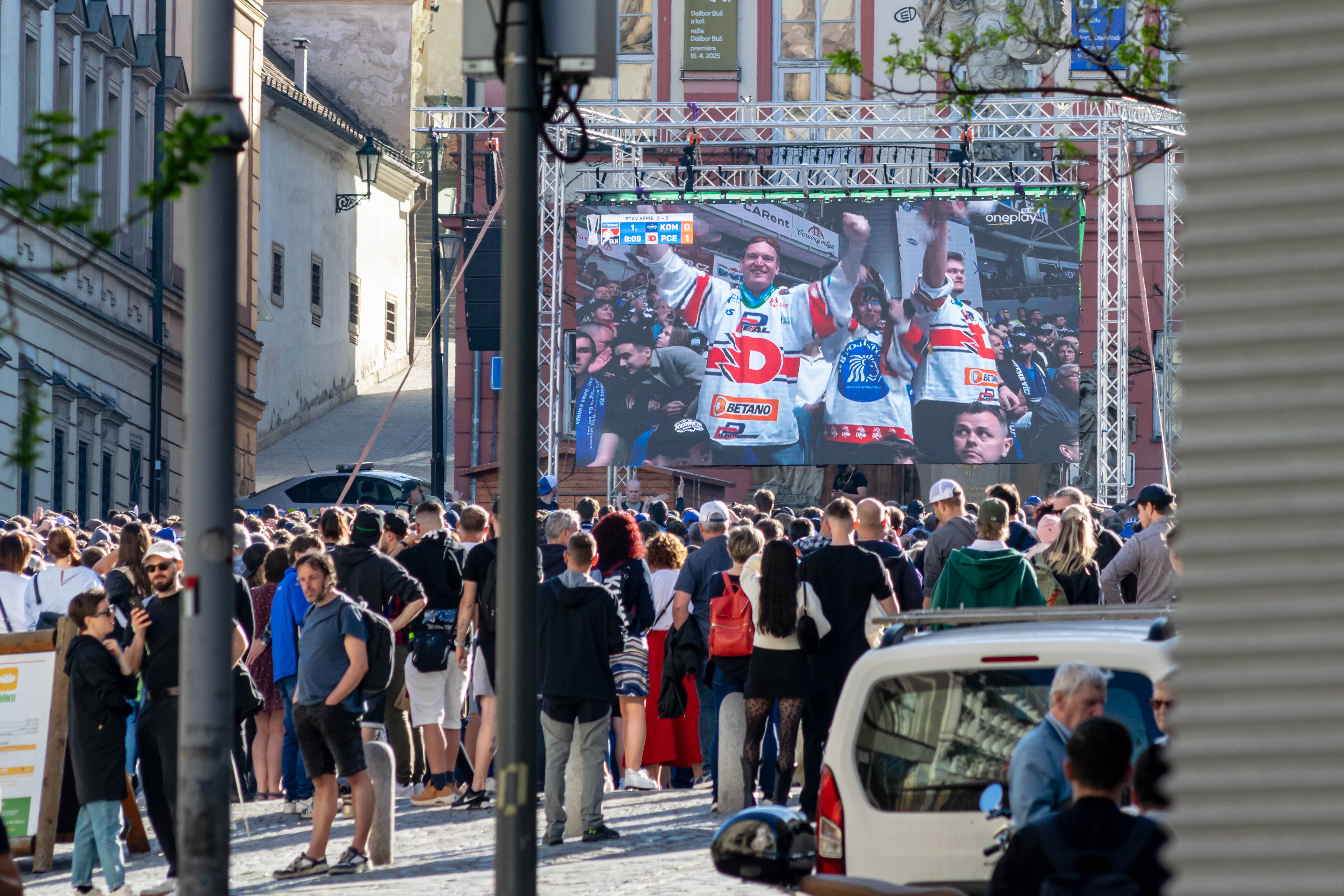 crowd of people watching a hockey match on an outdoors screen