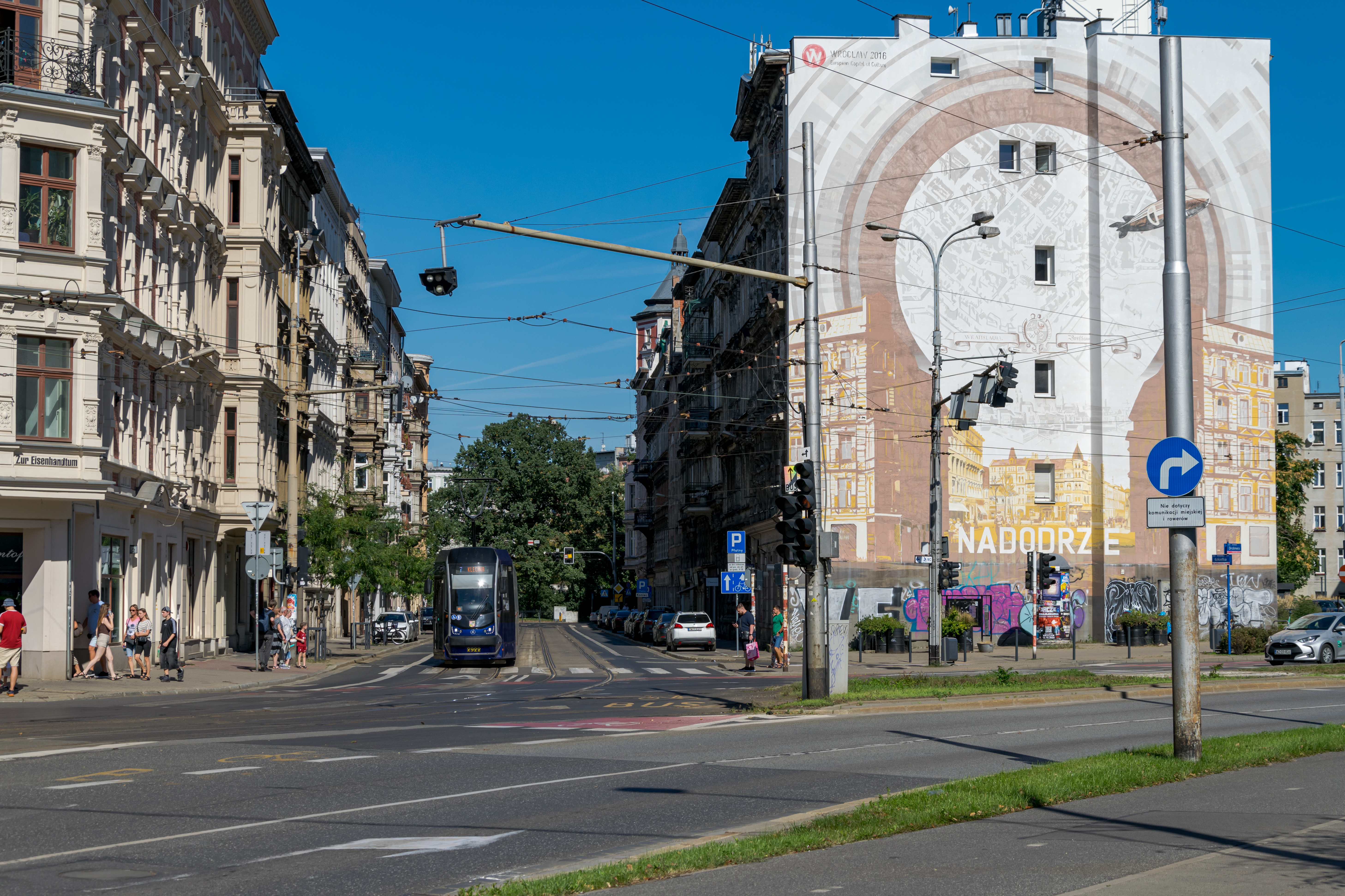 dark-blue tram next to a big mural illustrating this neighbourhood