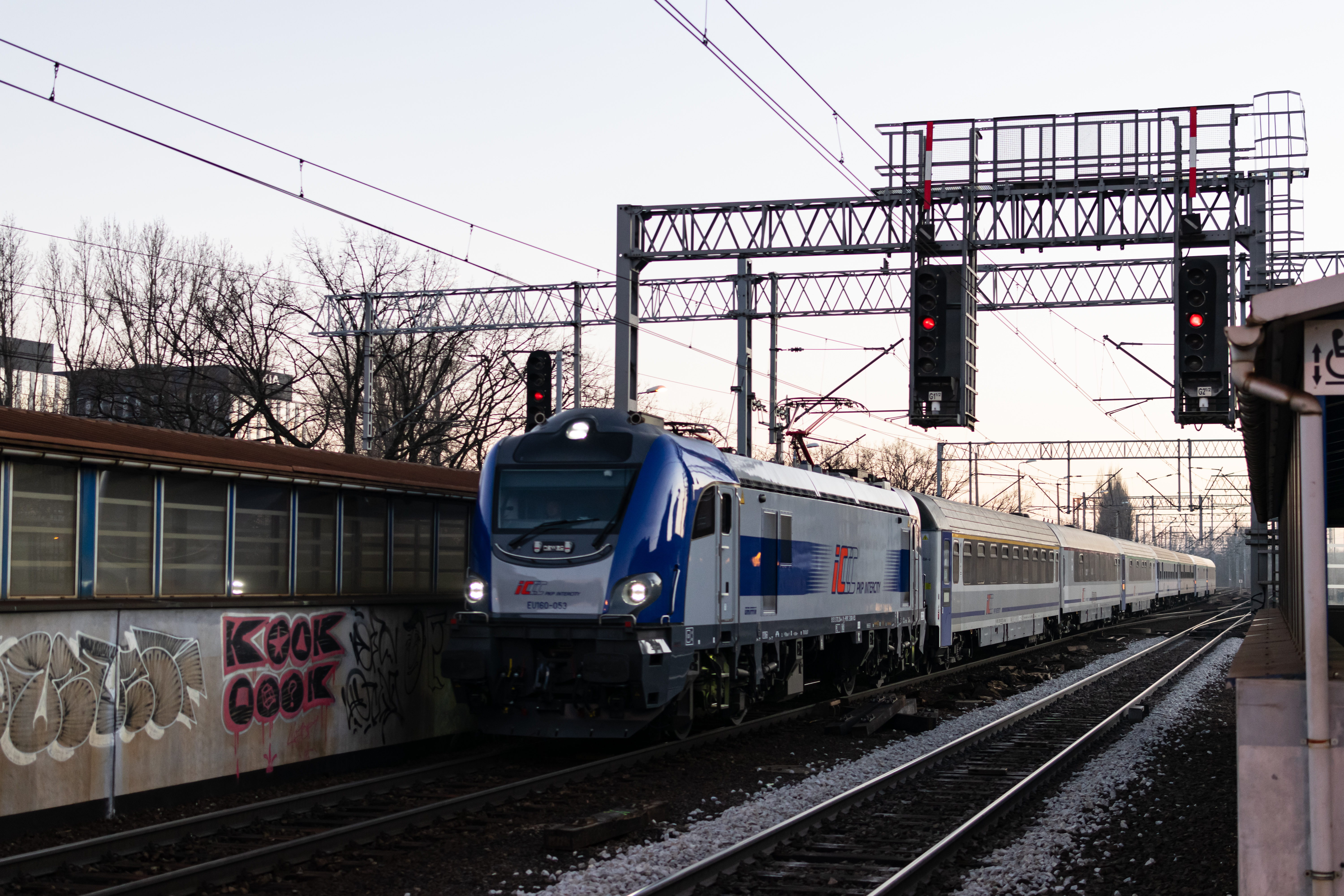 silver-blue EU160 pulling 8 coaches and speeding past the station