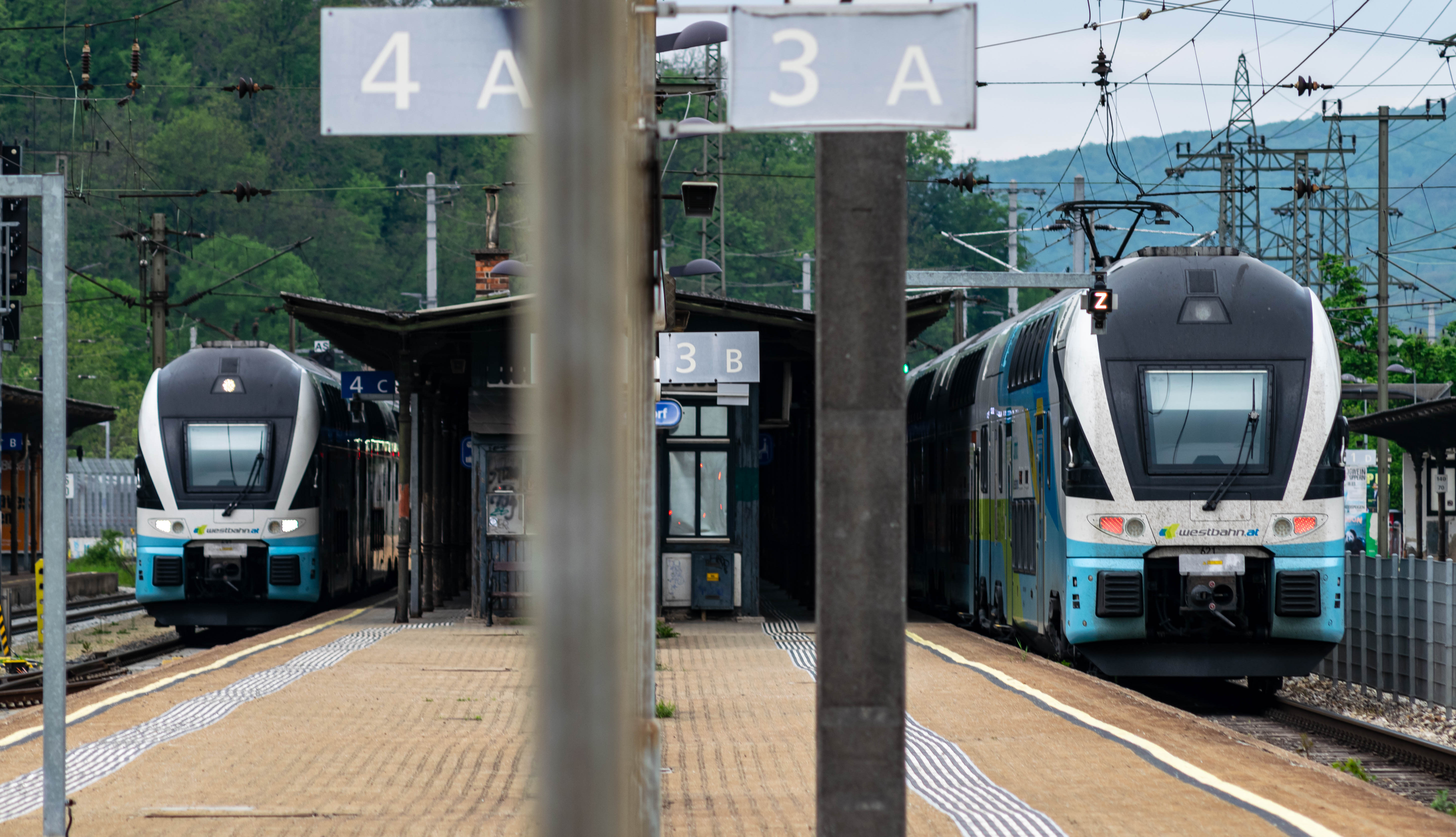 two white-blue double decker trains stopped at the same platform