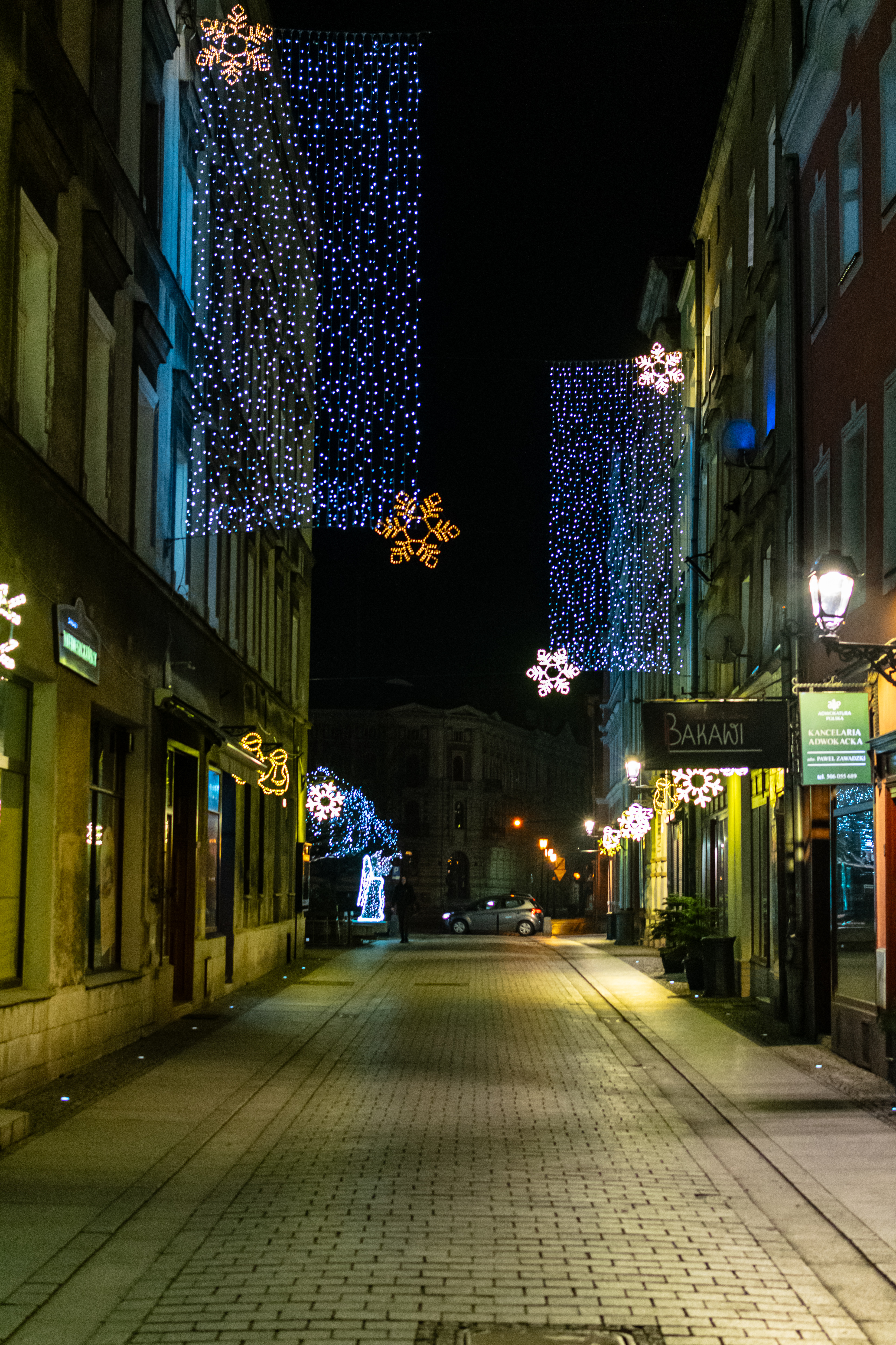 pedestrian street full of shops with tall christmas decorations
