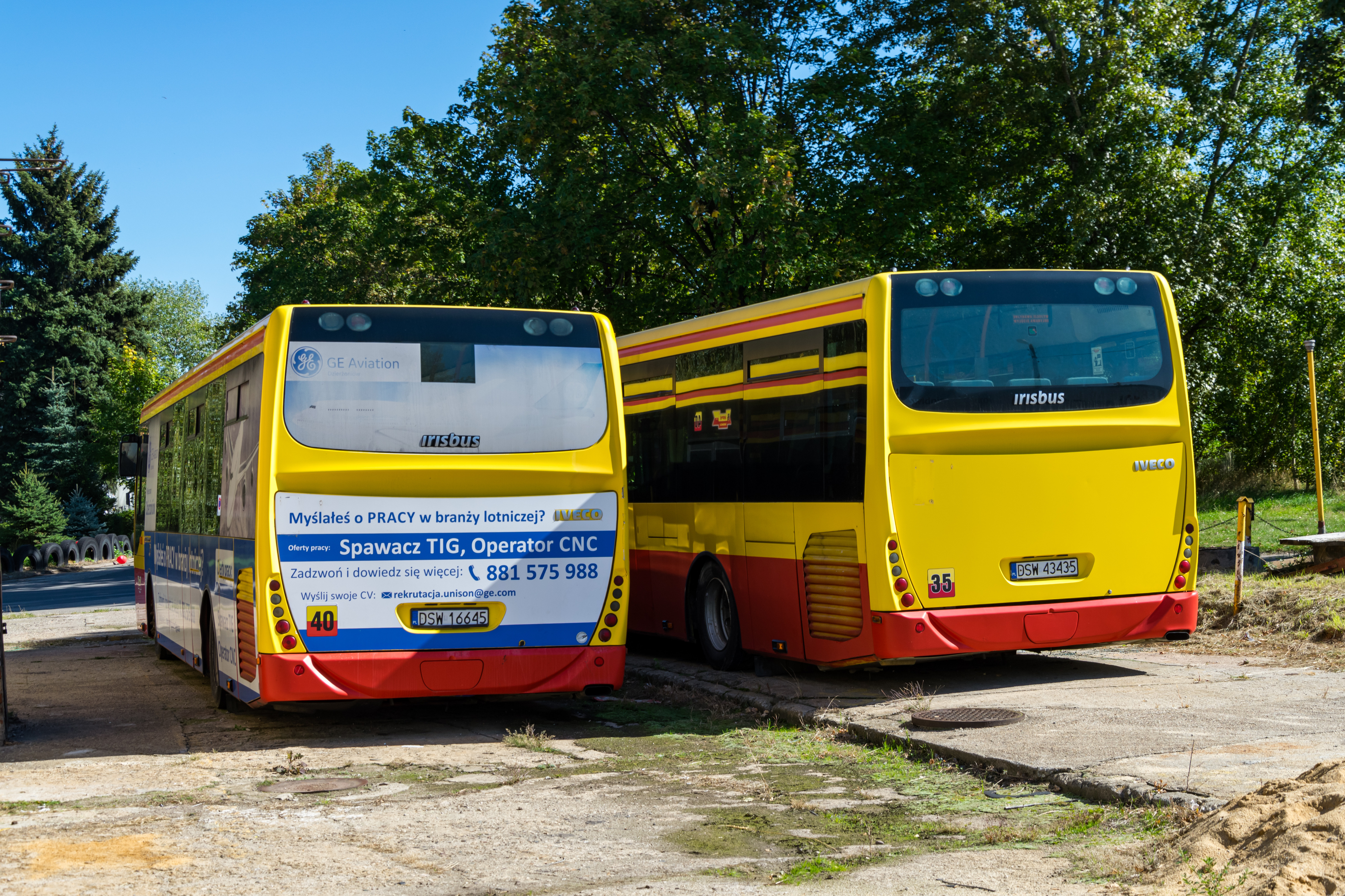 Two retired yellow-red Irisbus Crossway buses, left one still with ads on it