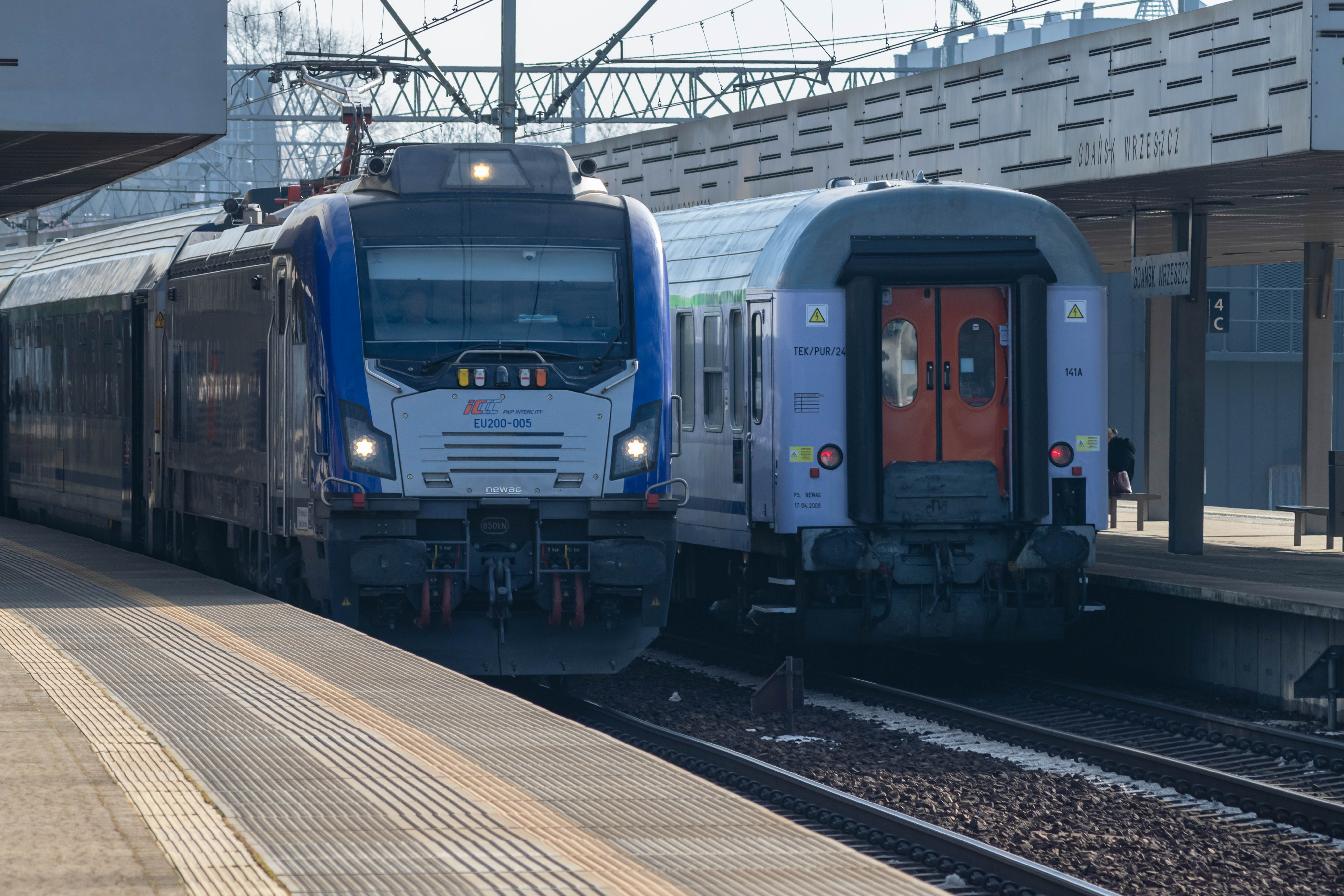 another blue-silver locomotive pulling coaches, standing next to an end of different train