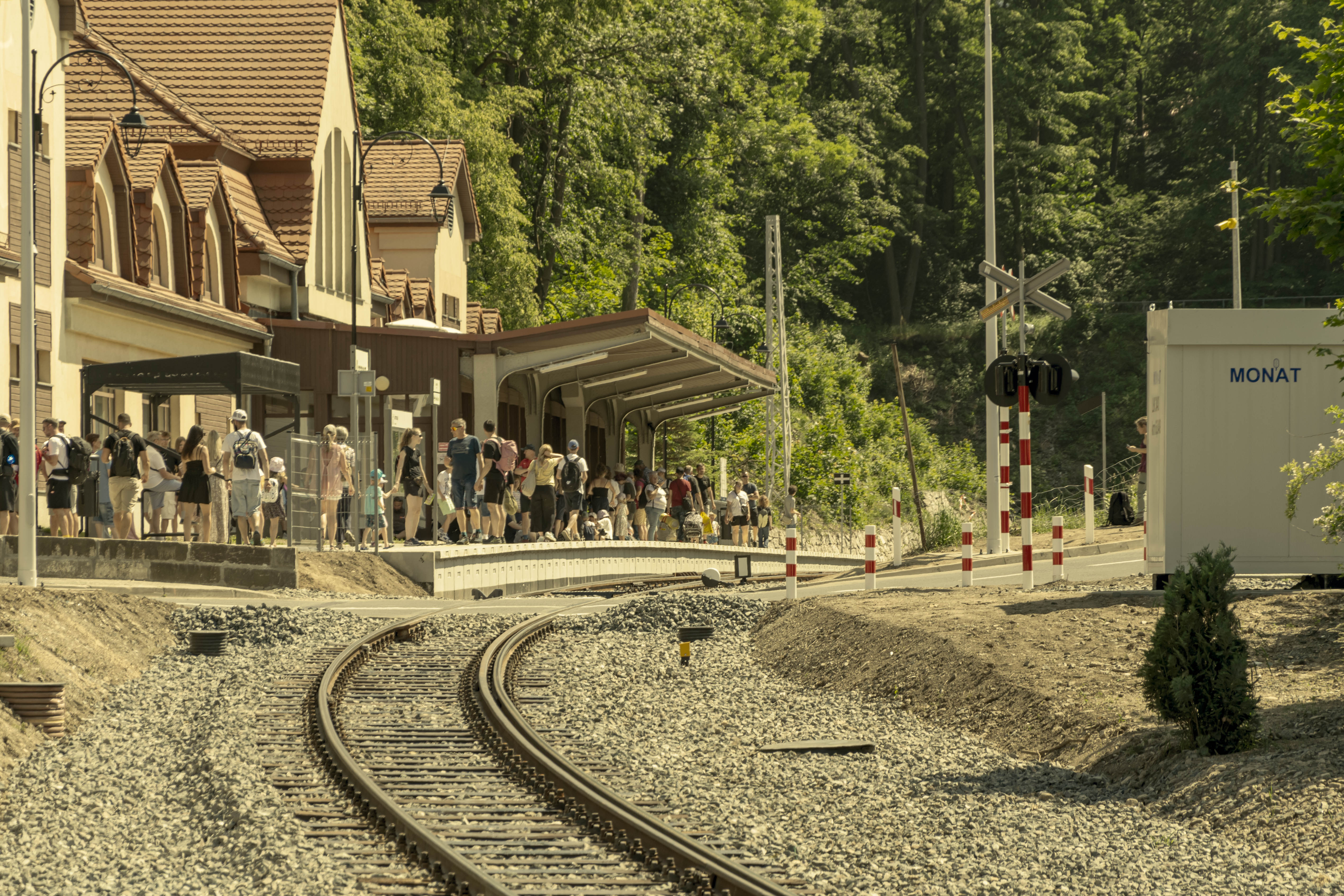 photo of a curved track and an overcrowded platform, photo has a yellow tint