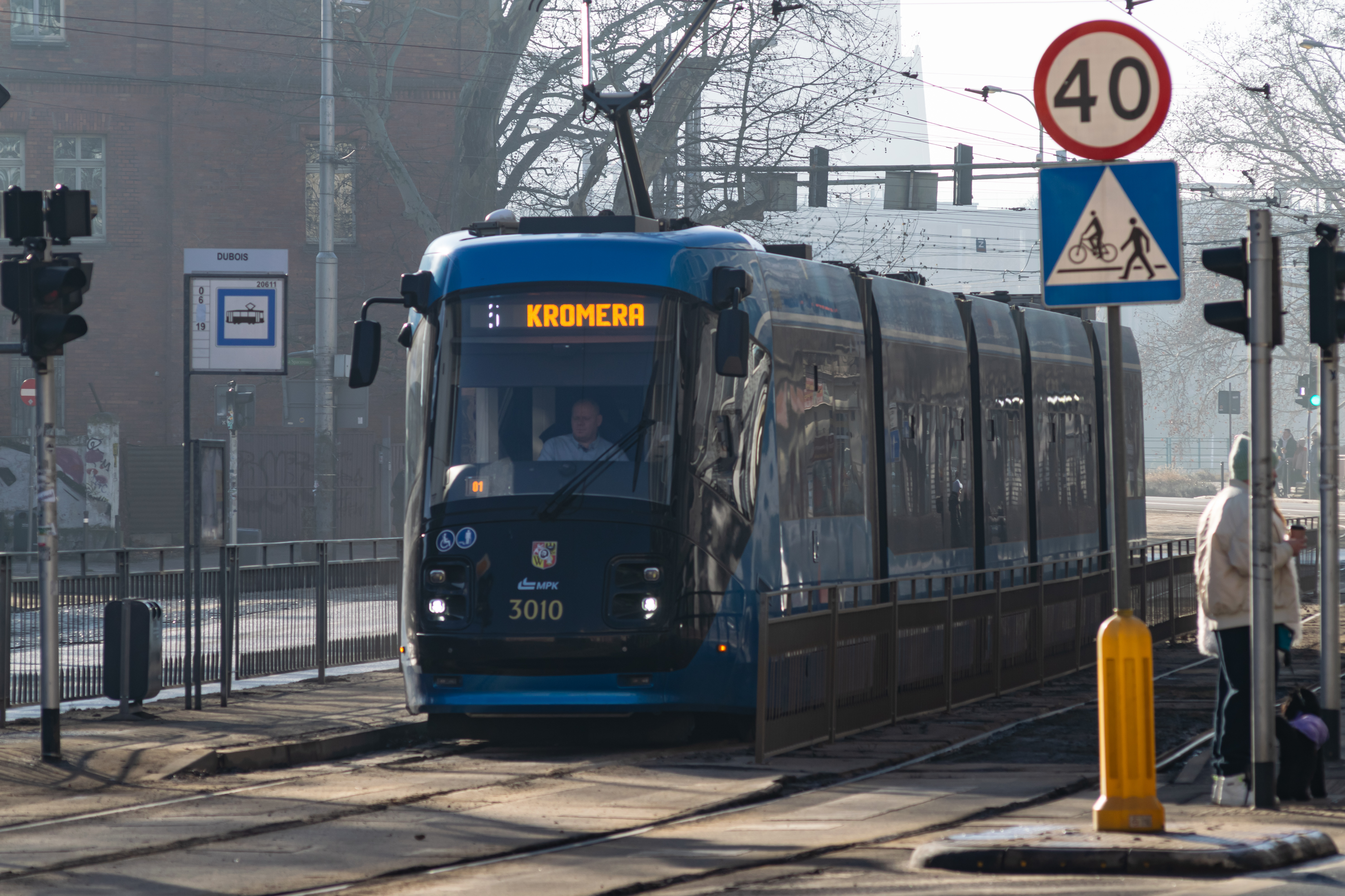 blue Škoda 16T at a narrow tram stop