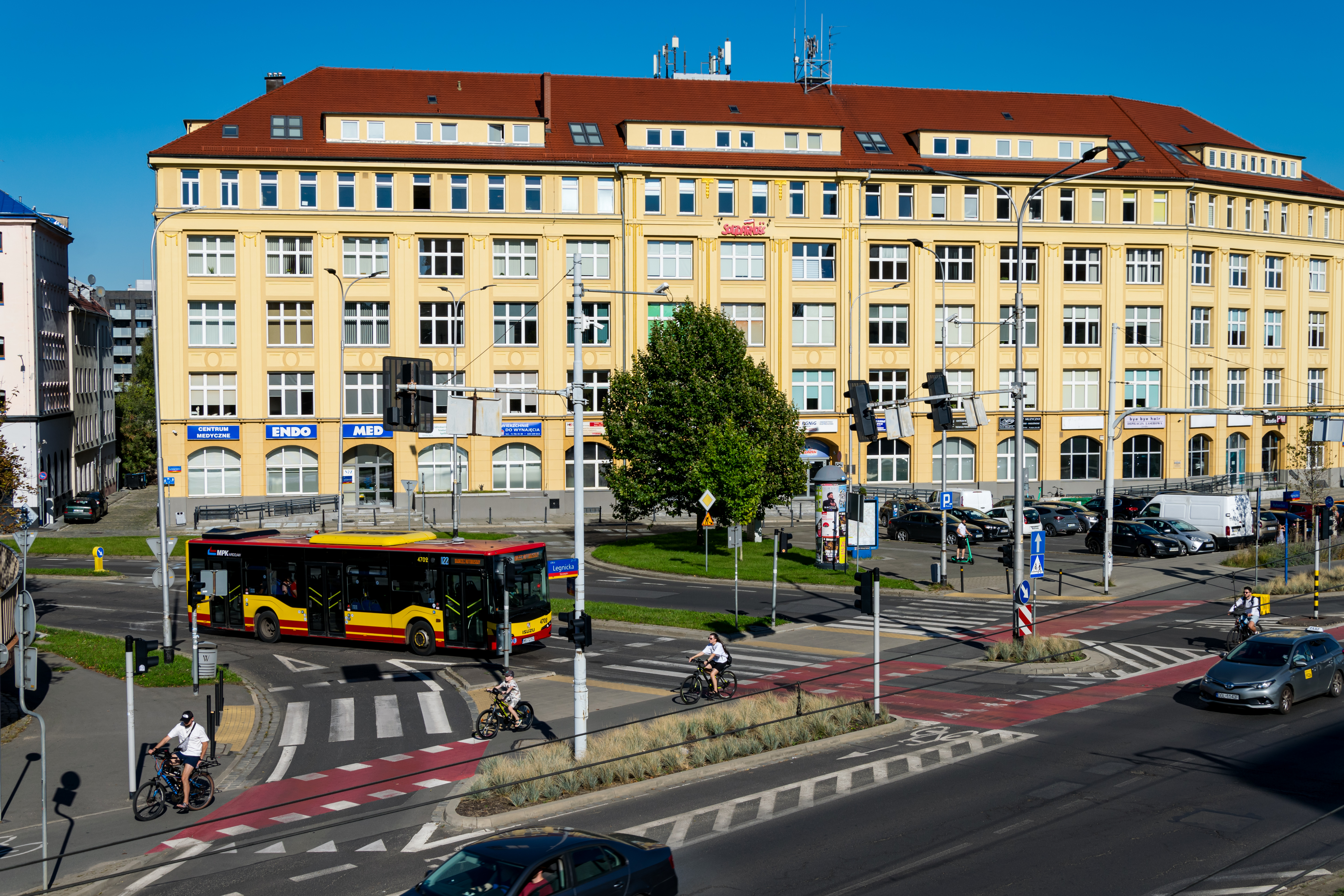 yellow-red bus with a big creamy building in background