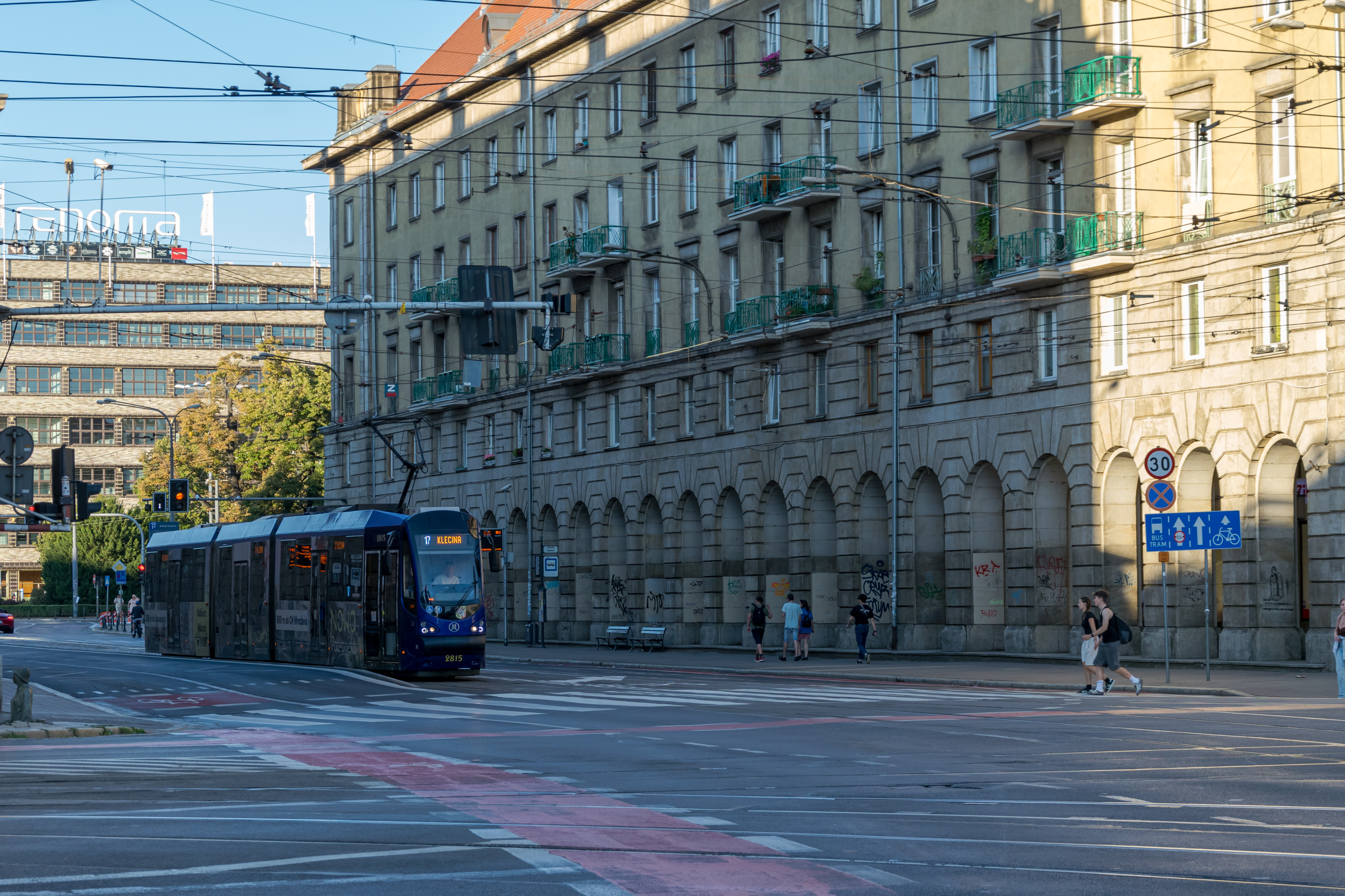 another dark-blue tram viewed from side on background of another old big building