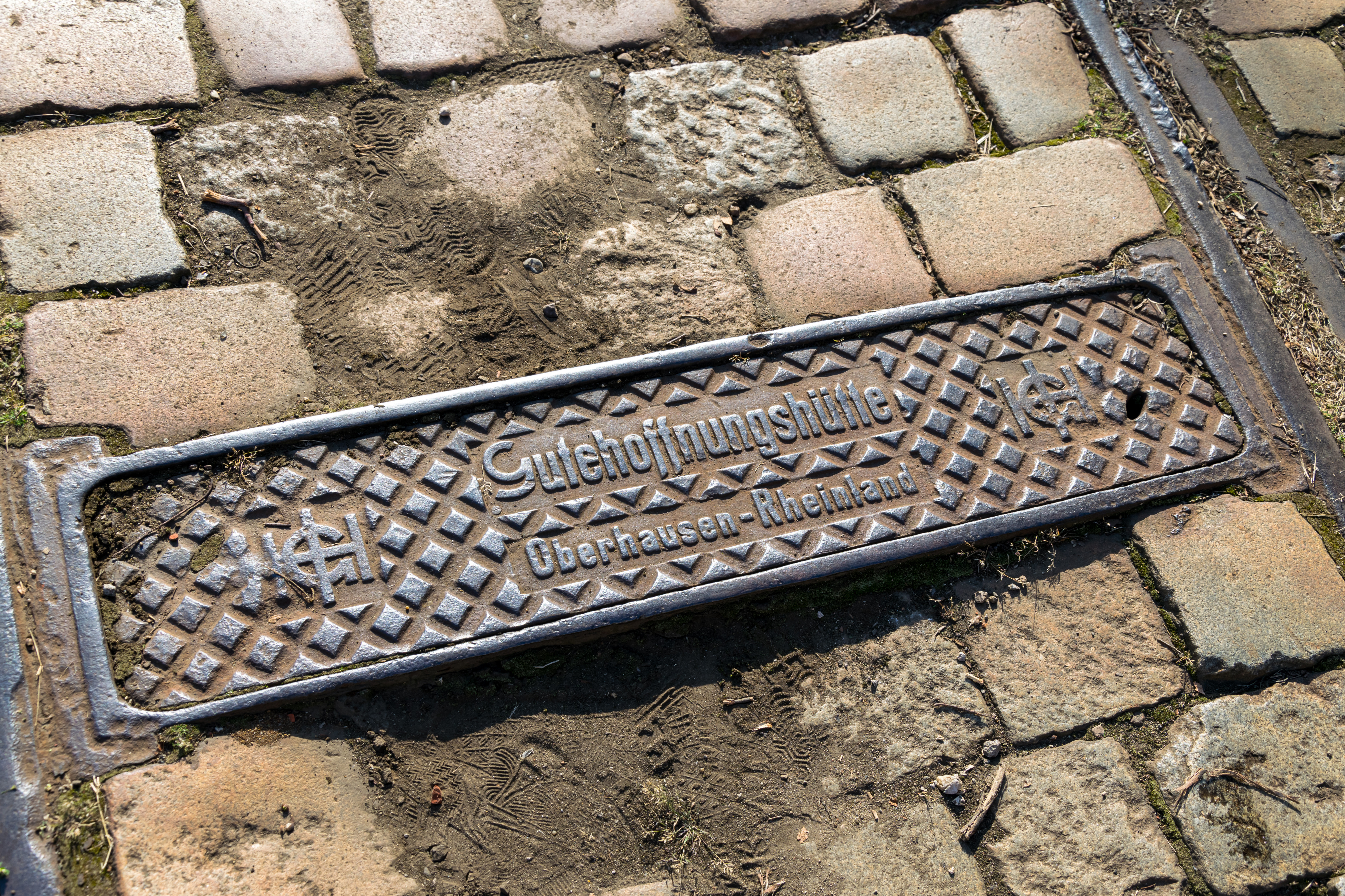 metal plaque embedded in cobblestone, reading „Gutehoffnungshütte, Oberhausen - Rheinland."