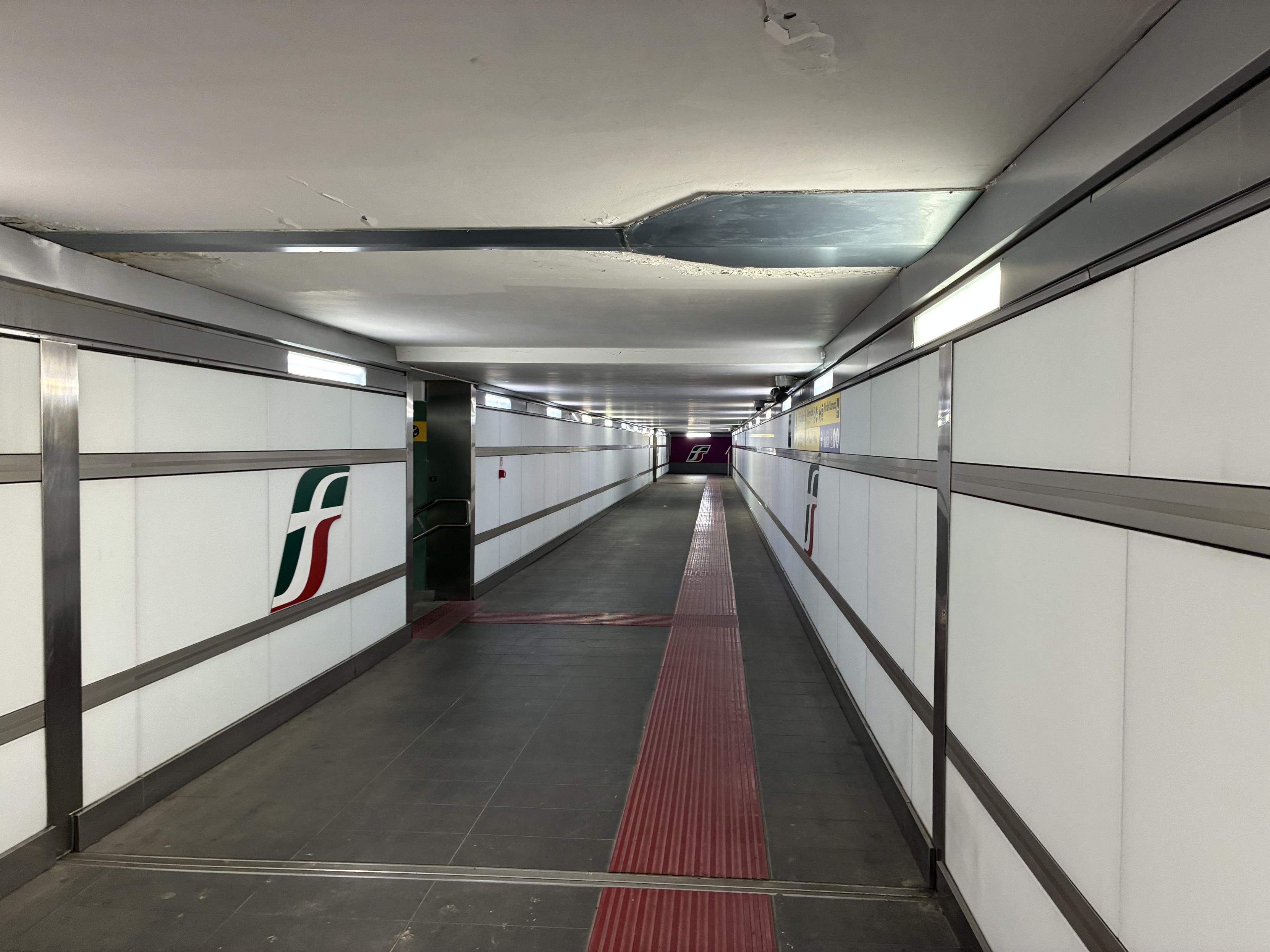 random tunnel with white paned walls and dark tiles, illuminated with bright lights