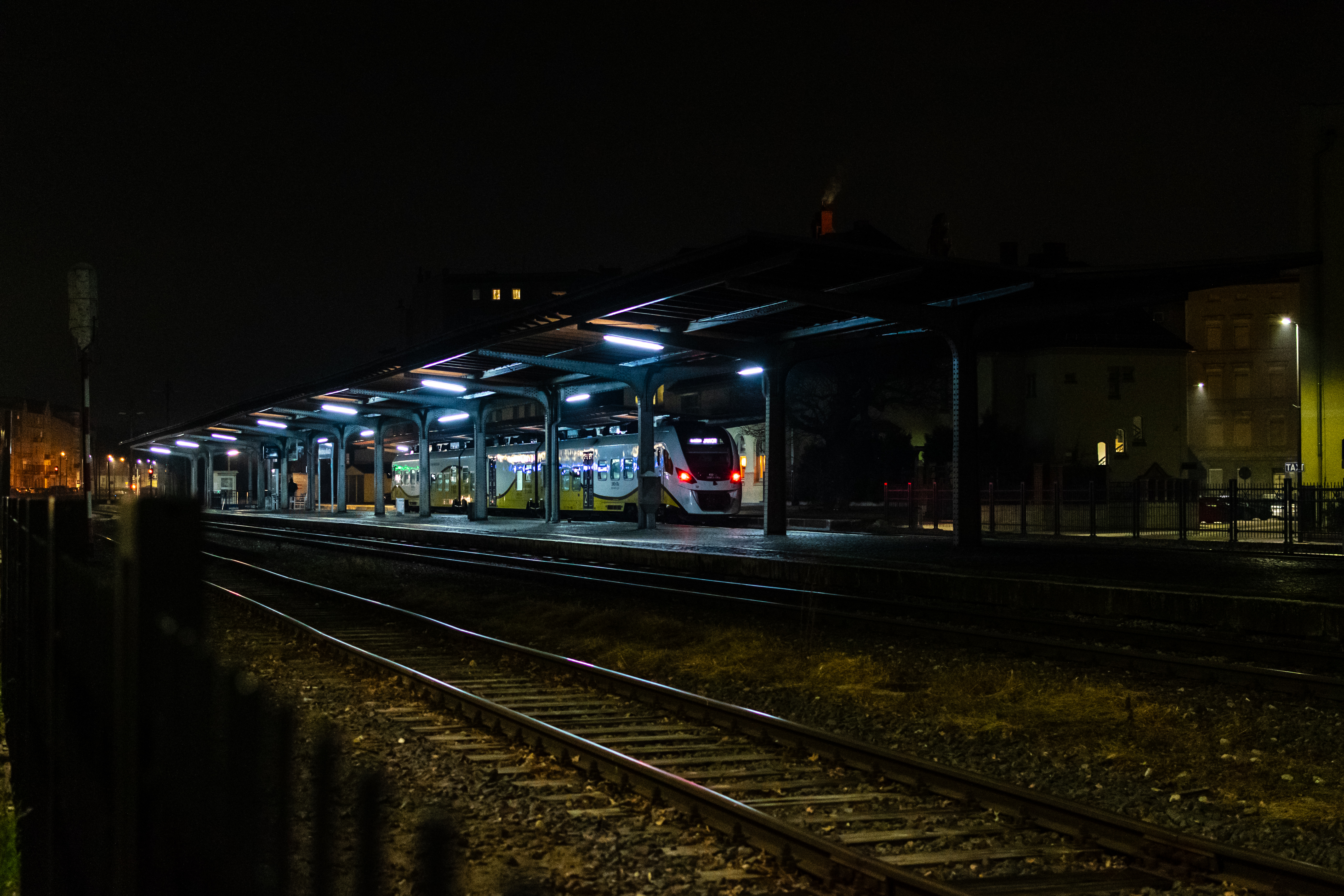 yellow-white train waiting at a train platform at night