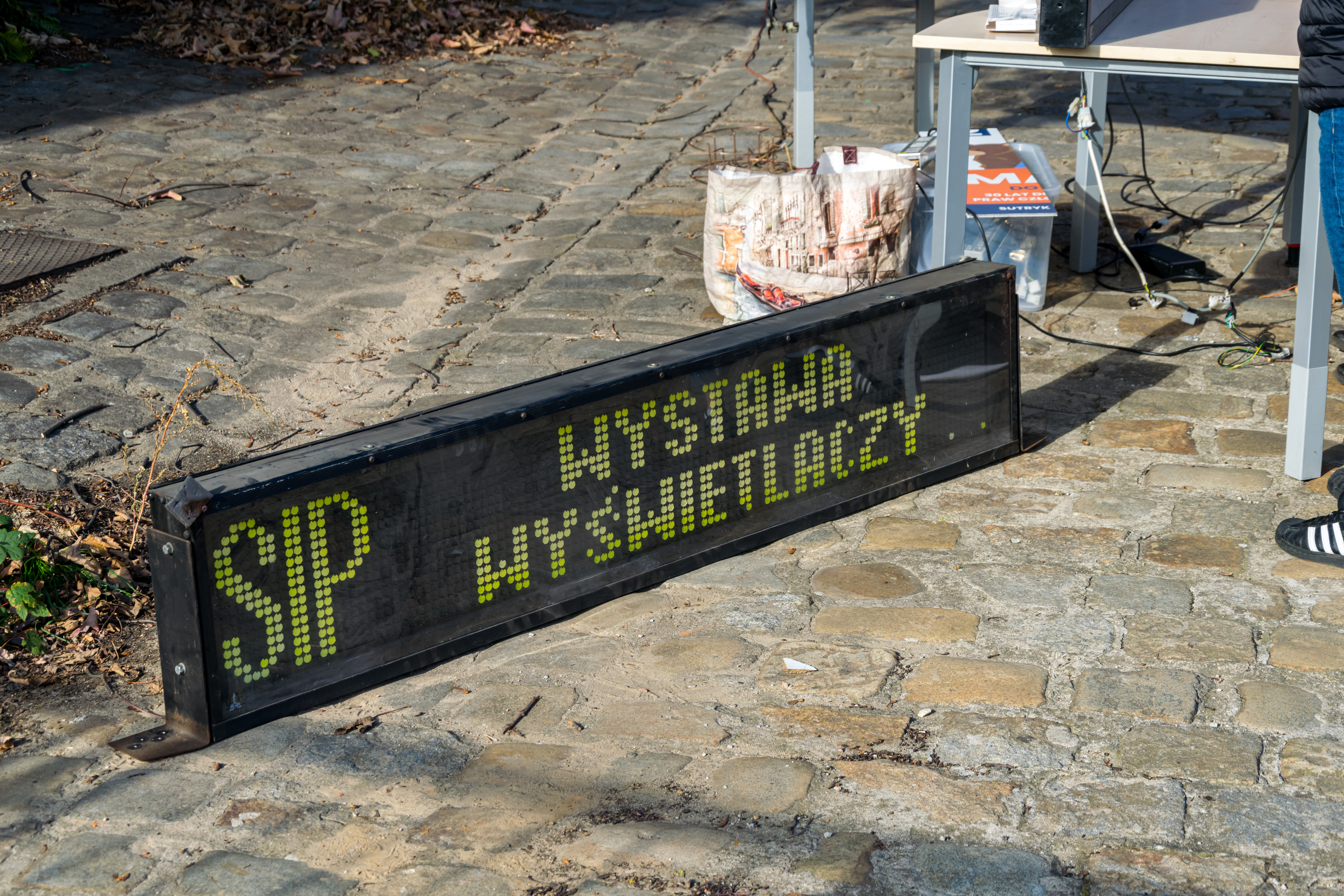Front destination display from a bus, on a cobblestone street showing „SIP - Display exposition”