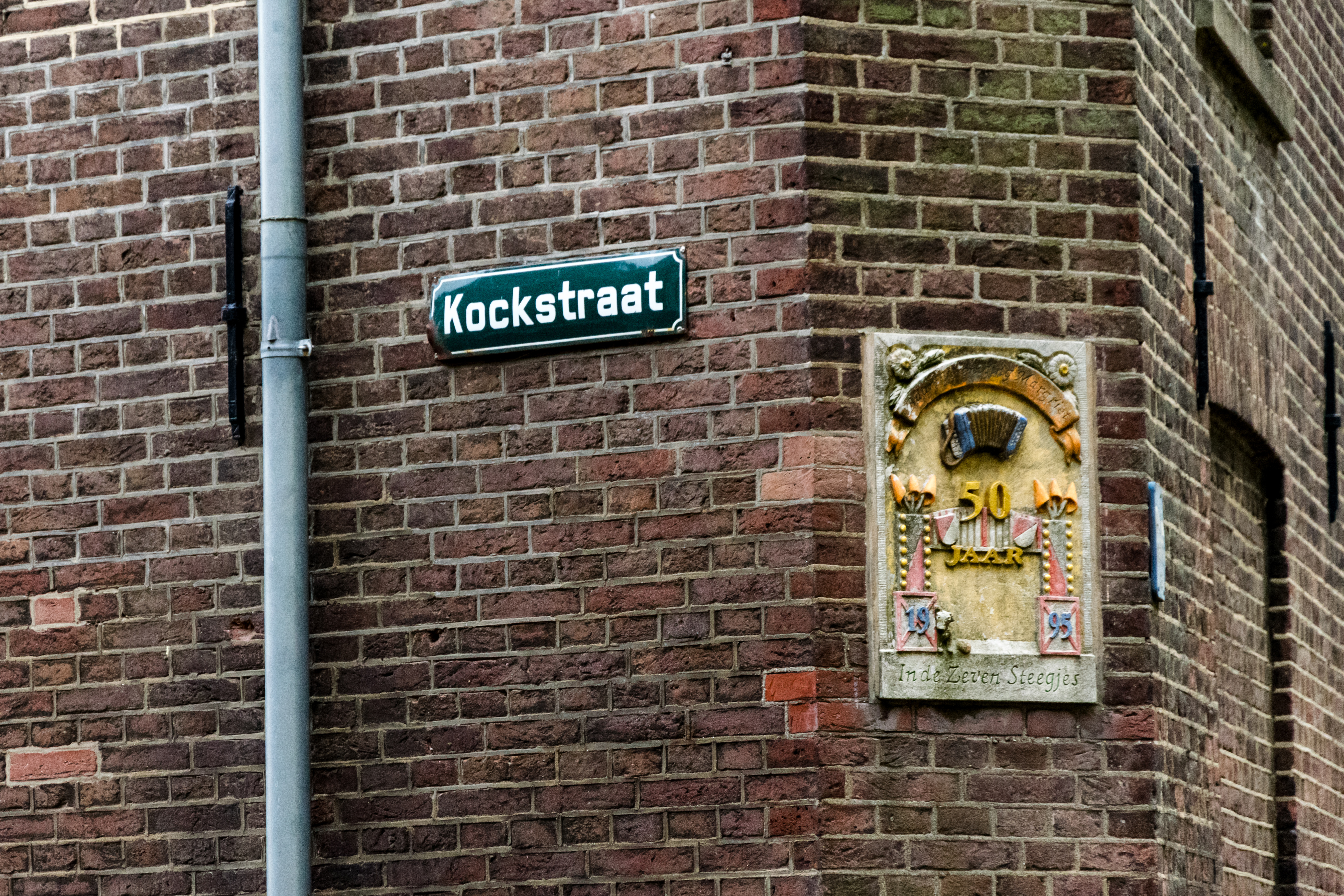 brick building corner with a plate saying "Kockstraat" and some plaque celebrating 50th anniversary of something 