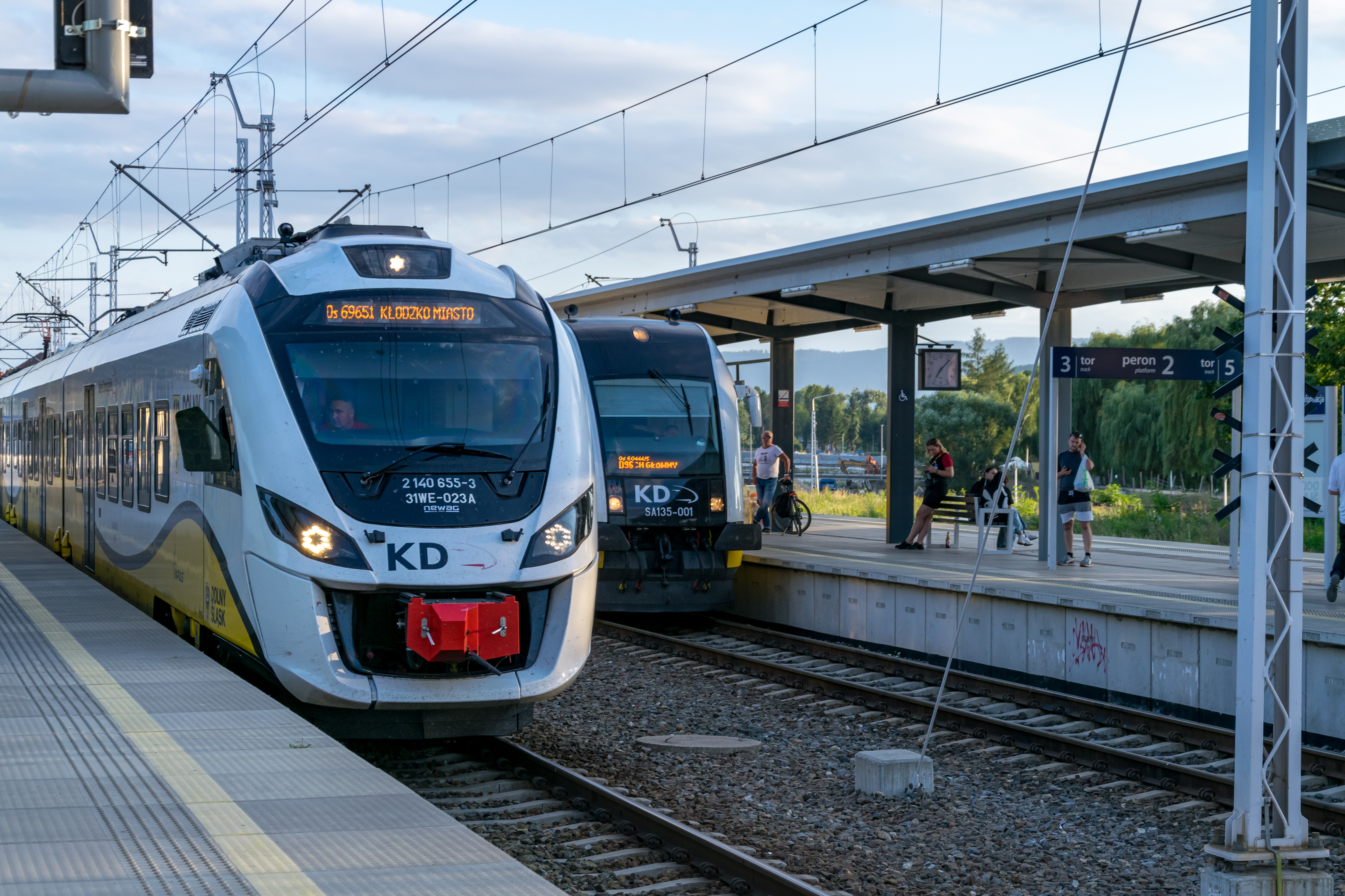 two yellow-white trains standing at platforms