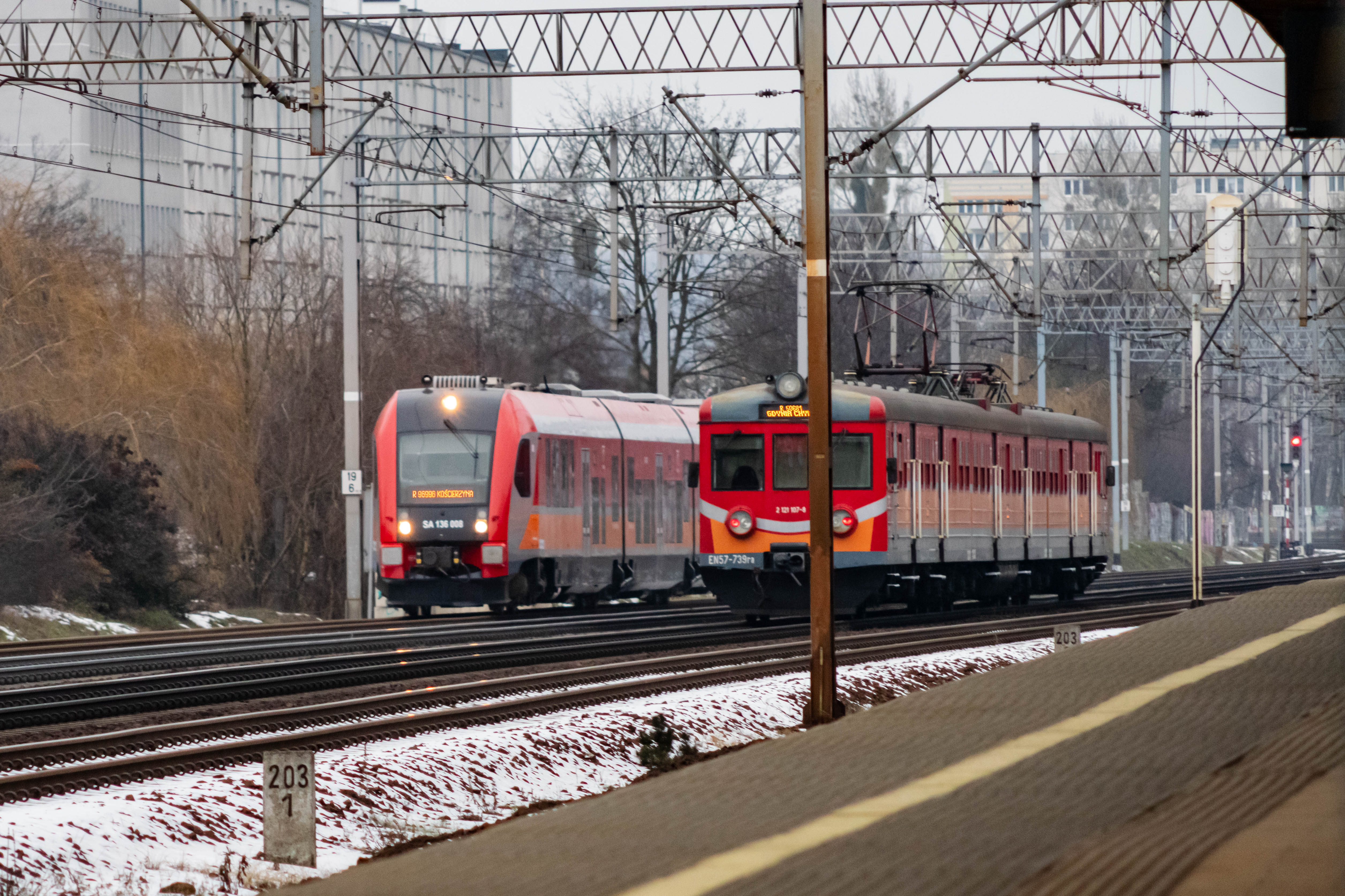 two red-silver-orange trains going past each other