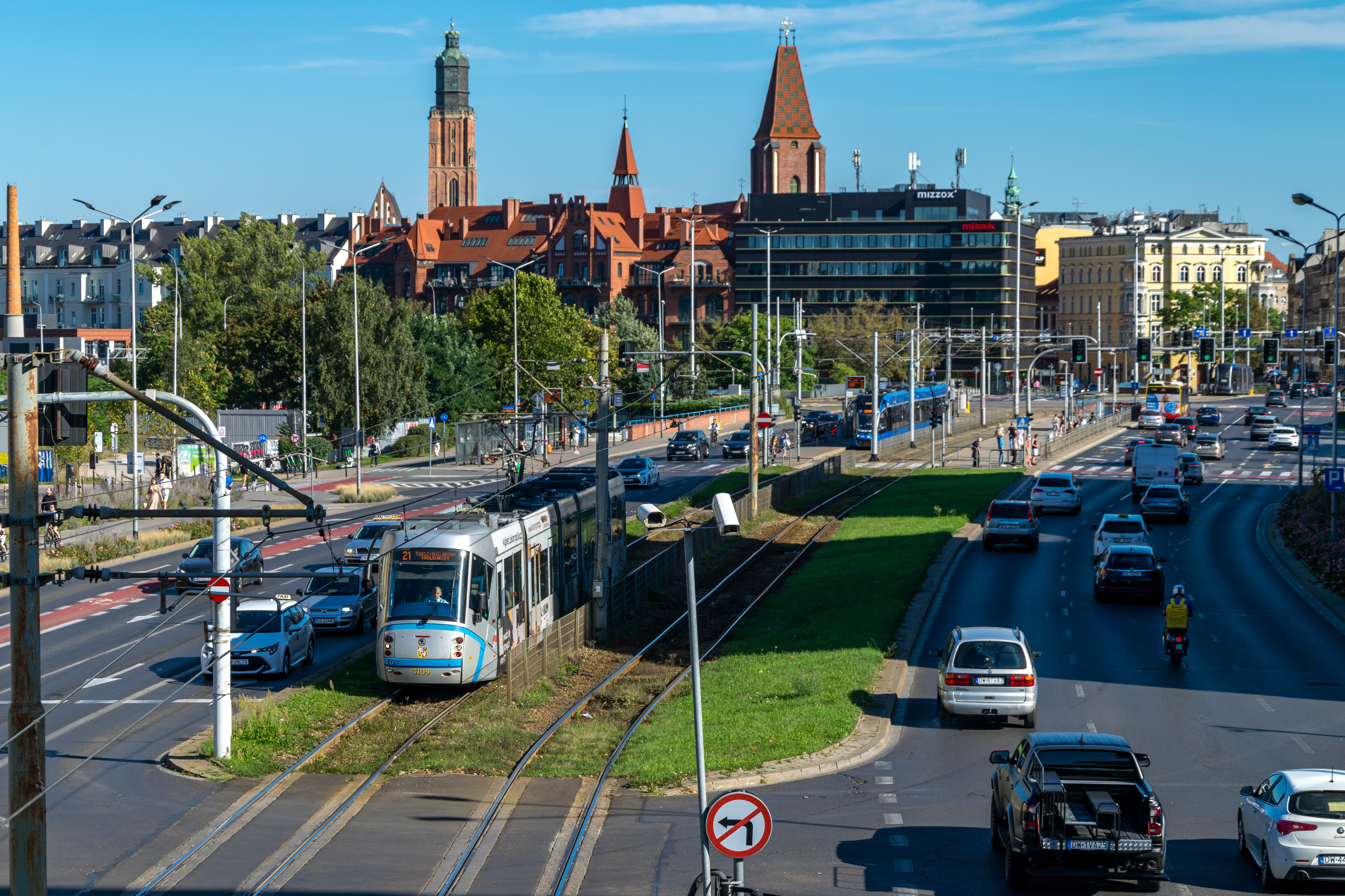 silver-blue tram viewed from a bridge, with a cityscape in background