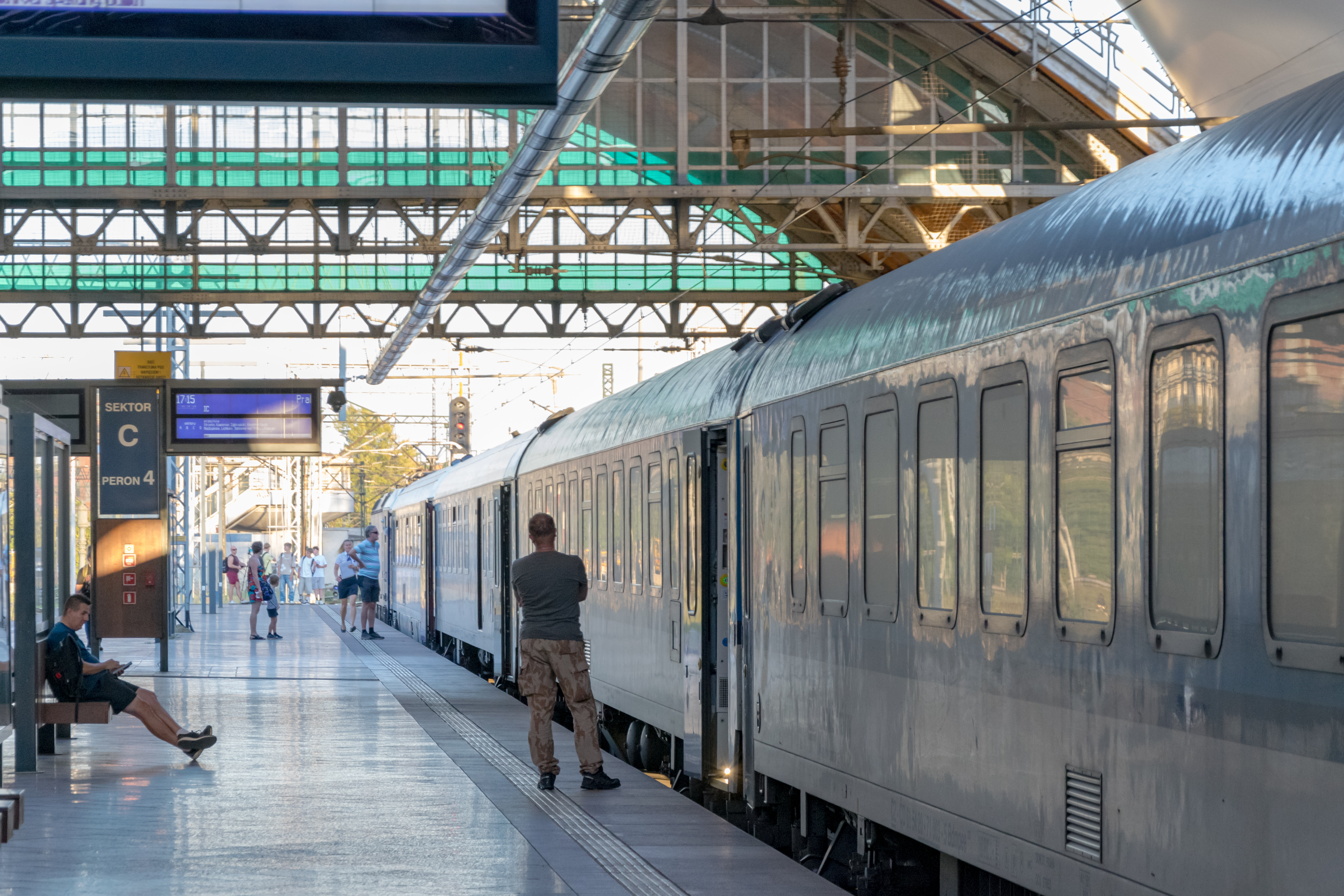 white-blue coaches next to a platform with a bunch of stressed passengers wondering why their train is not going for past hour