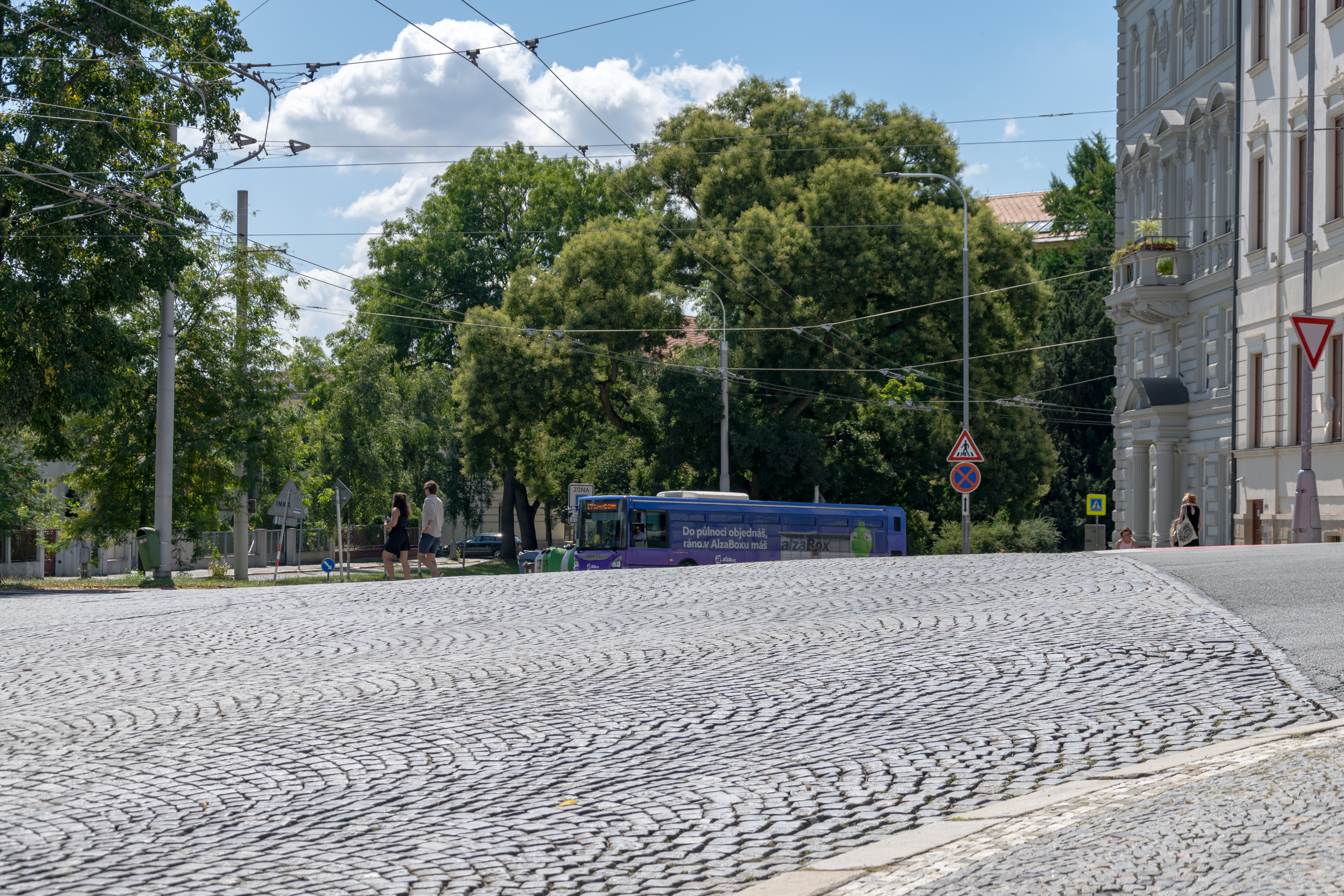a purple bus obscured by a street sloping upwards 