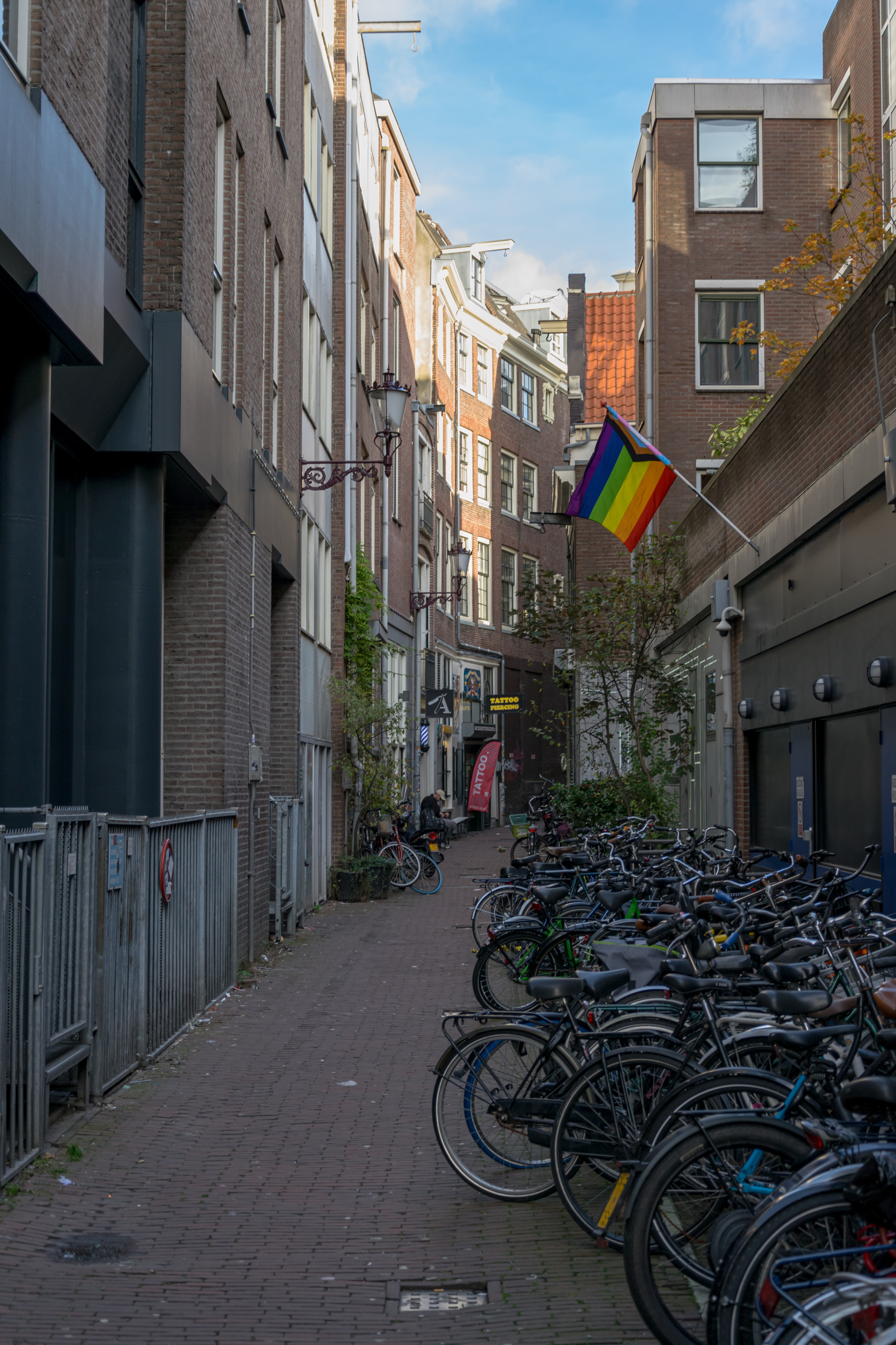 side alley with lots of bikes, and there's a progress pride flag