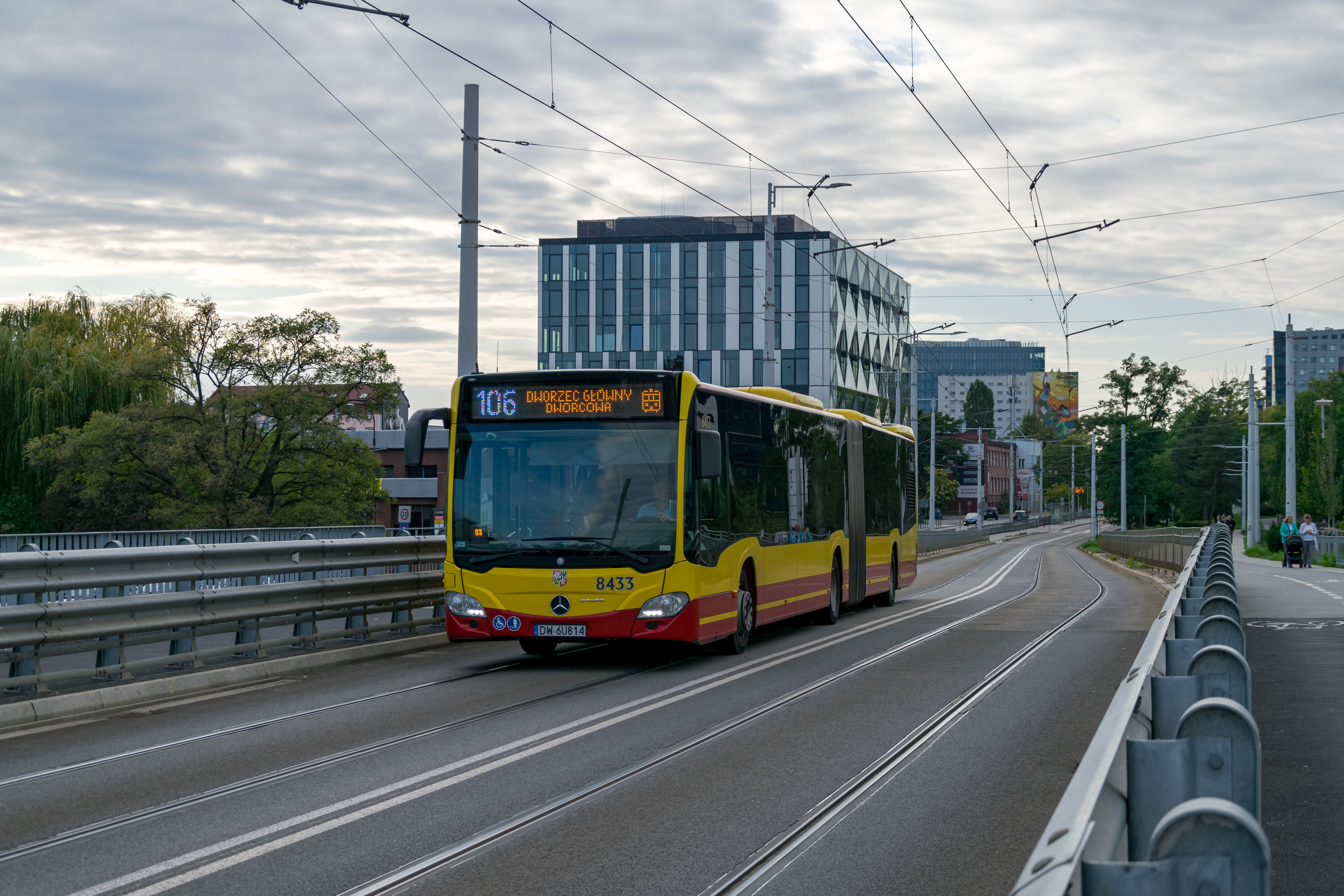 Yellow-red articulated Citaro bus at a bridge