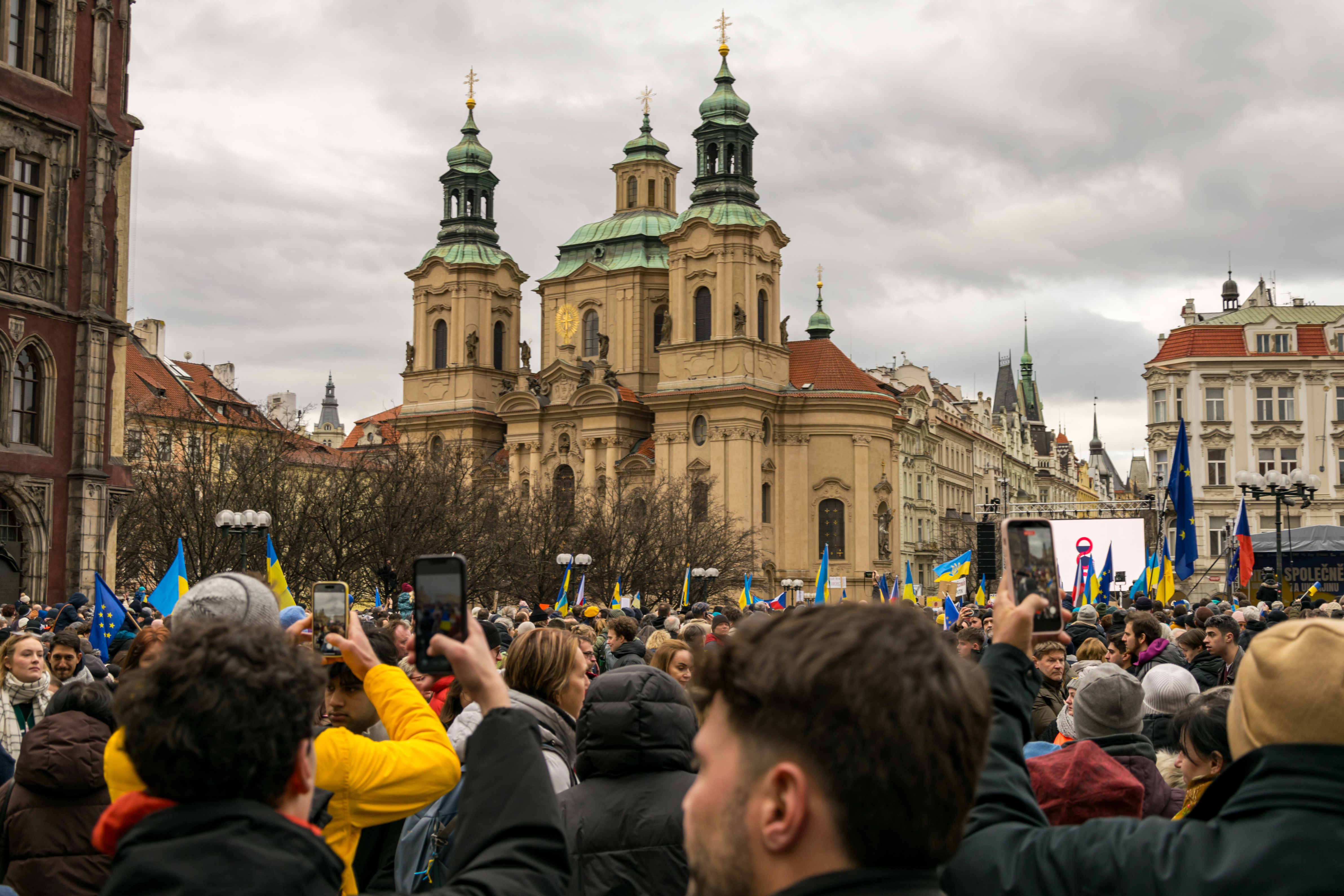 Old town square full of protesters, there’s a lot of Ukrainian flags