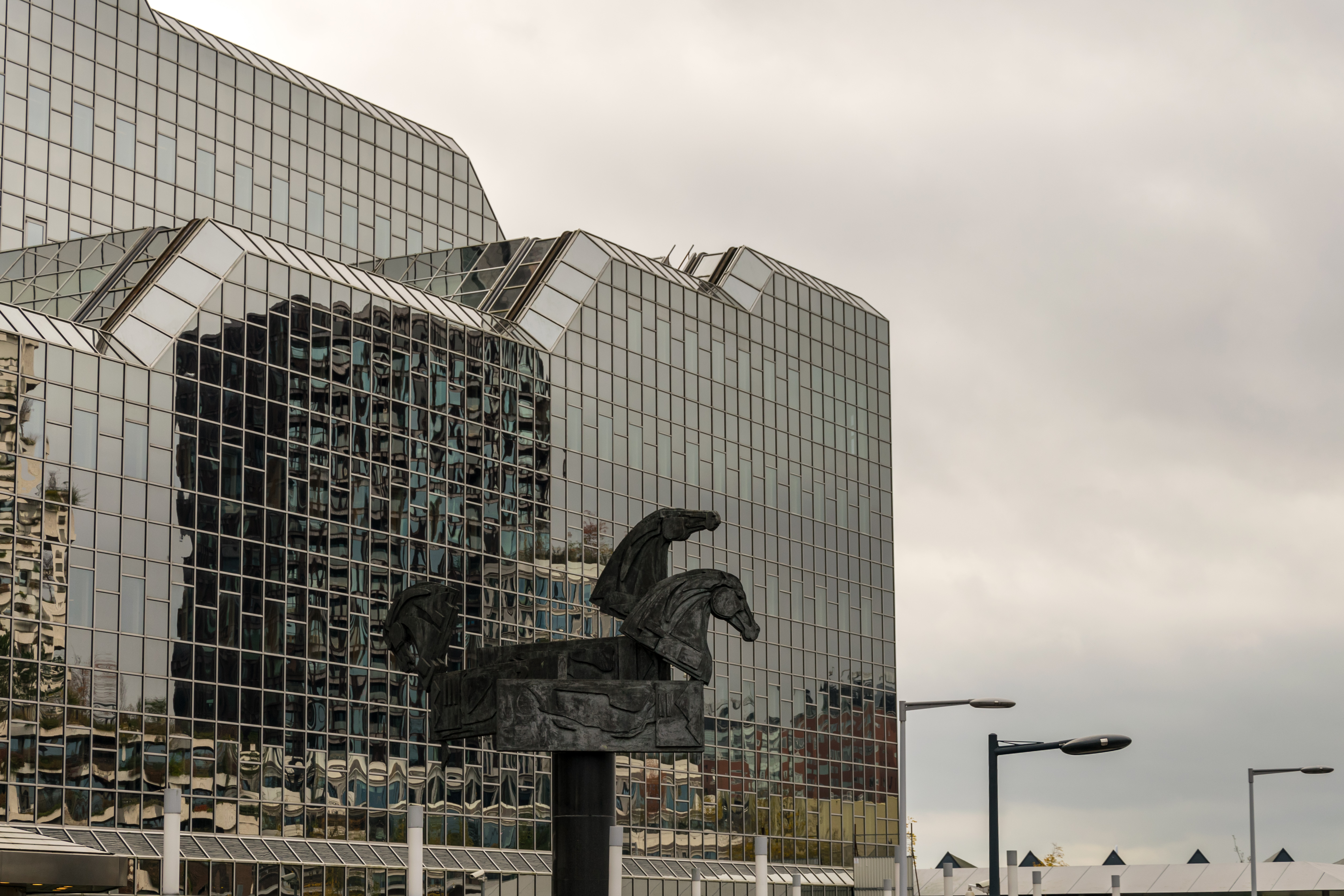 some horse statue thingy with a very glass house building in the background