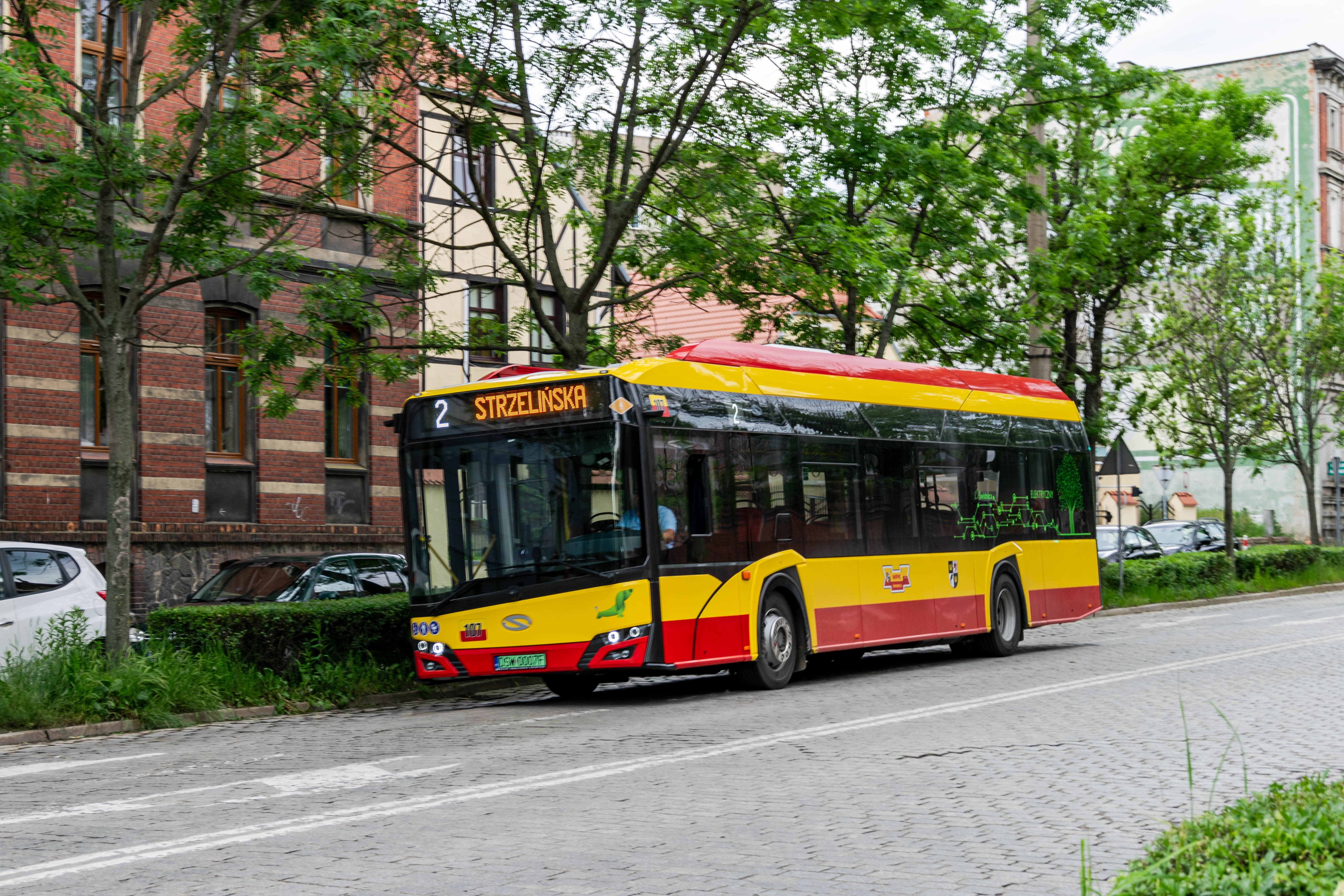 yellow-red electric bus going on a cobblestone street