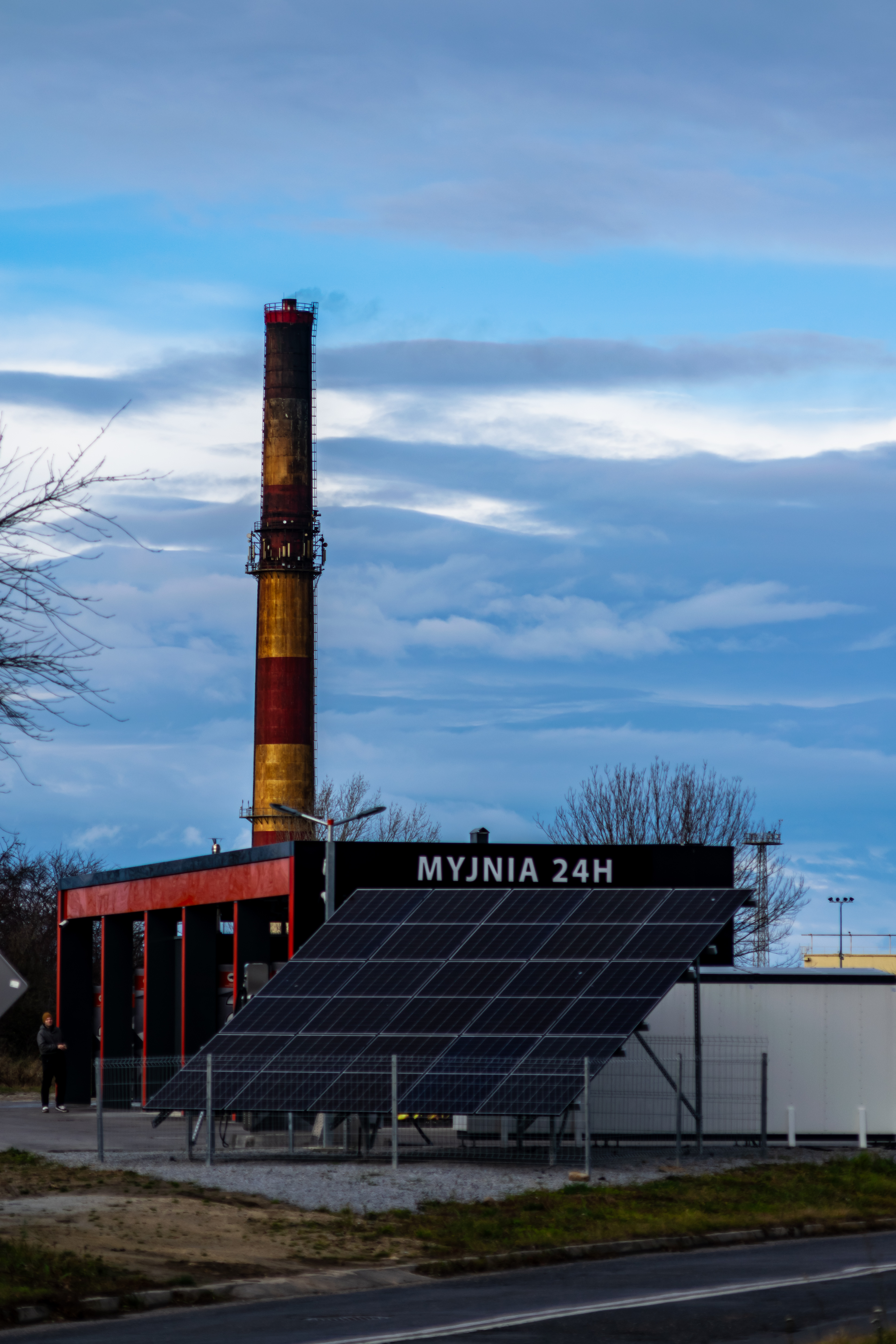 solar panels next to a car wash, with a huge chimney in the background