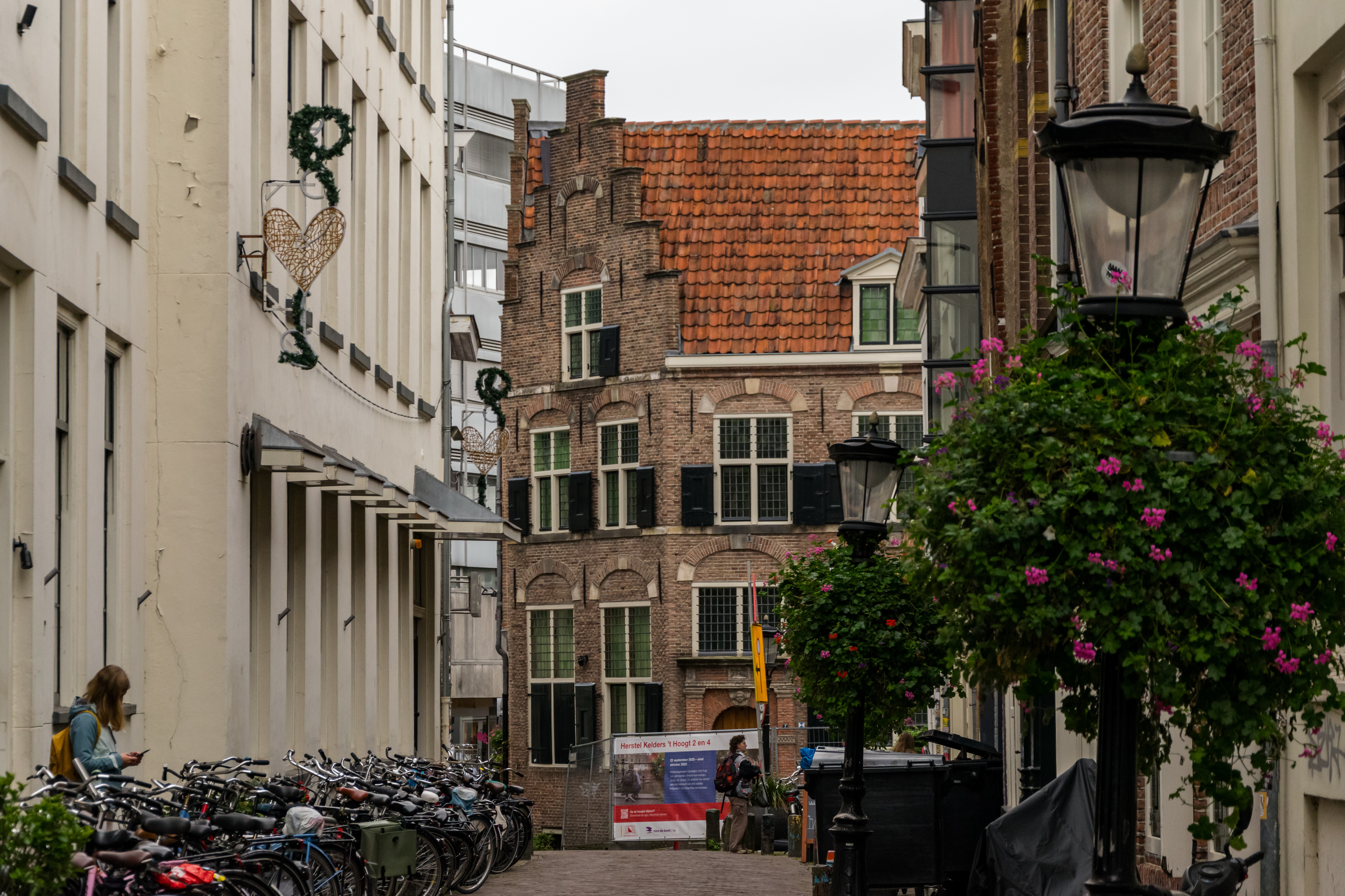 narrow street with Lots Of Bikes and a brick building at the end
