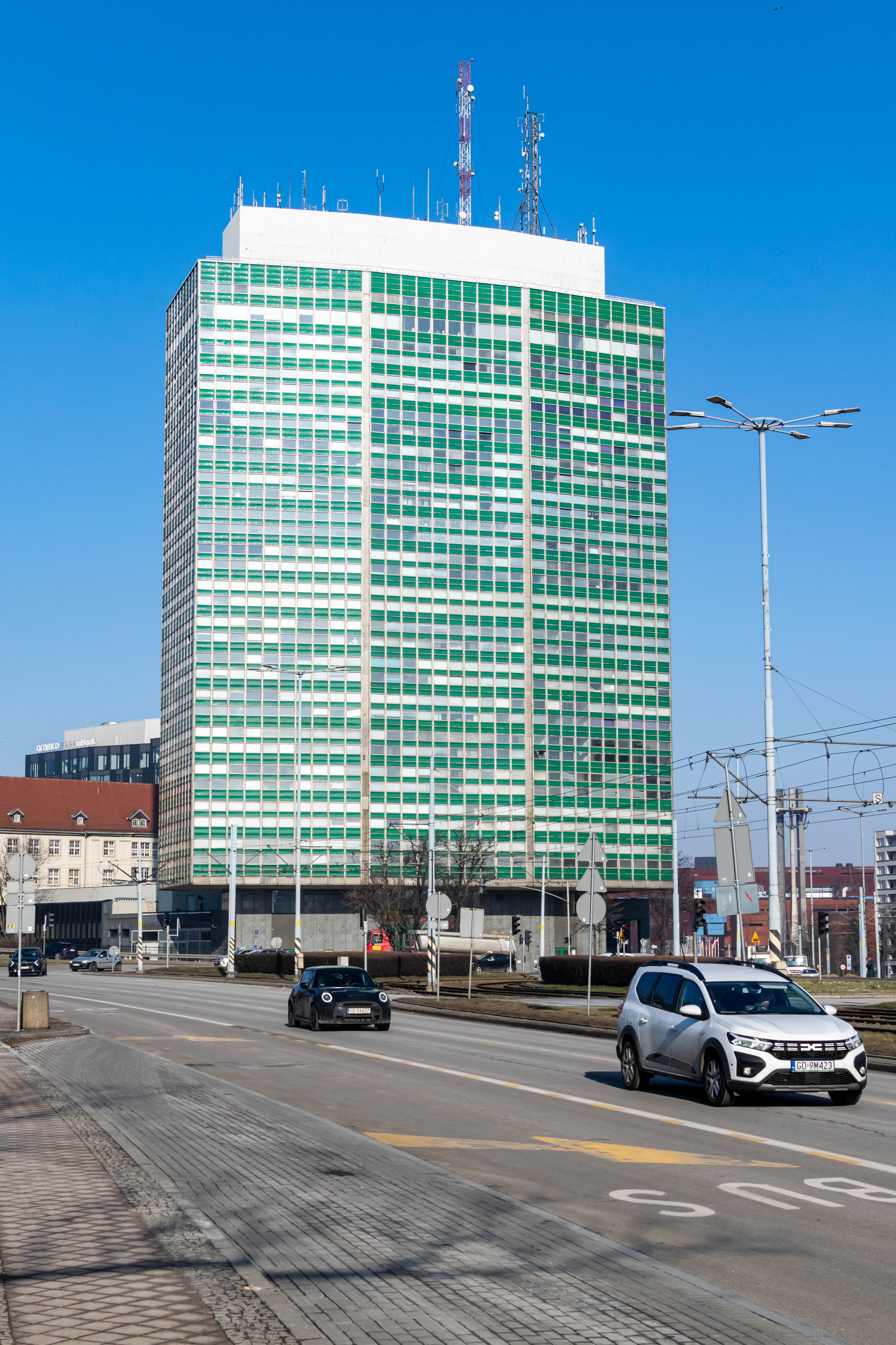 large modernist office building next to a busy street with cars and tram tracks