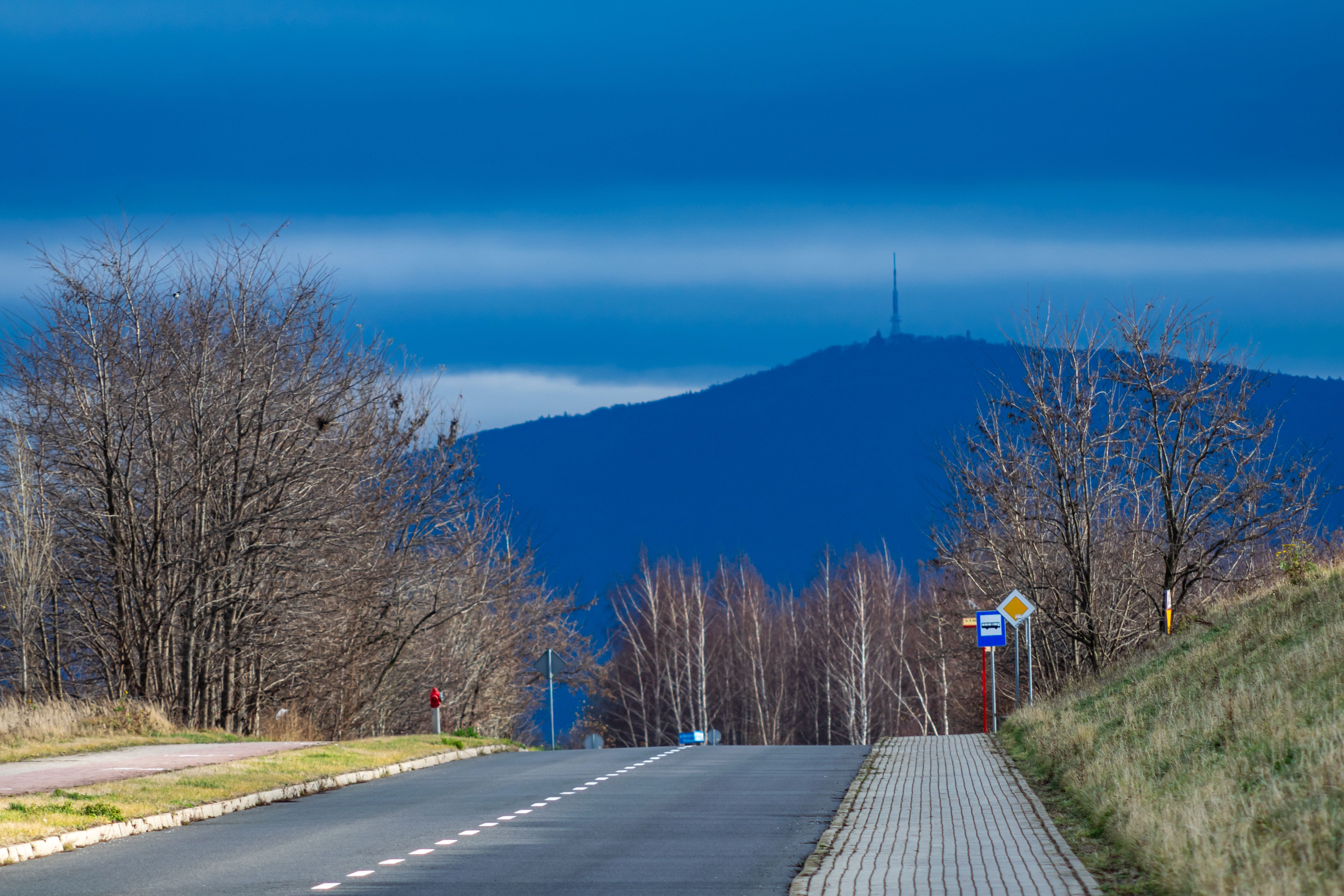 big mountain with a TV tower on top looming from behind the street