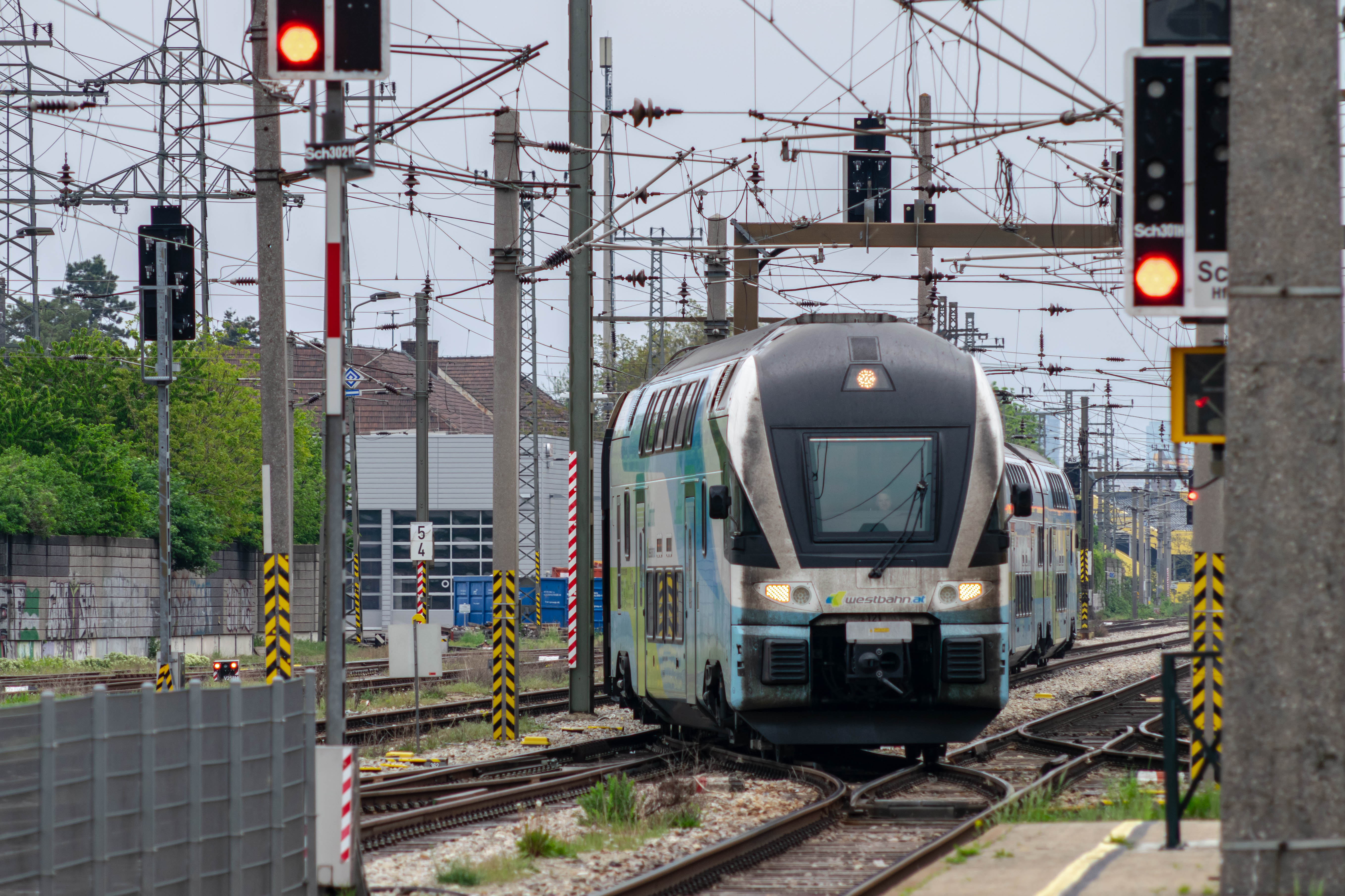dirty white-blue double-decker train changing tracks and arriving at the platform