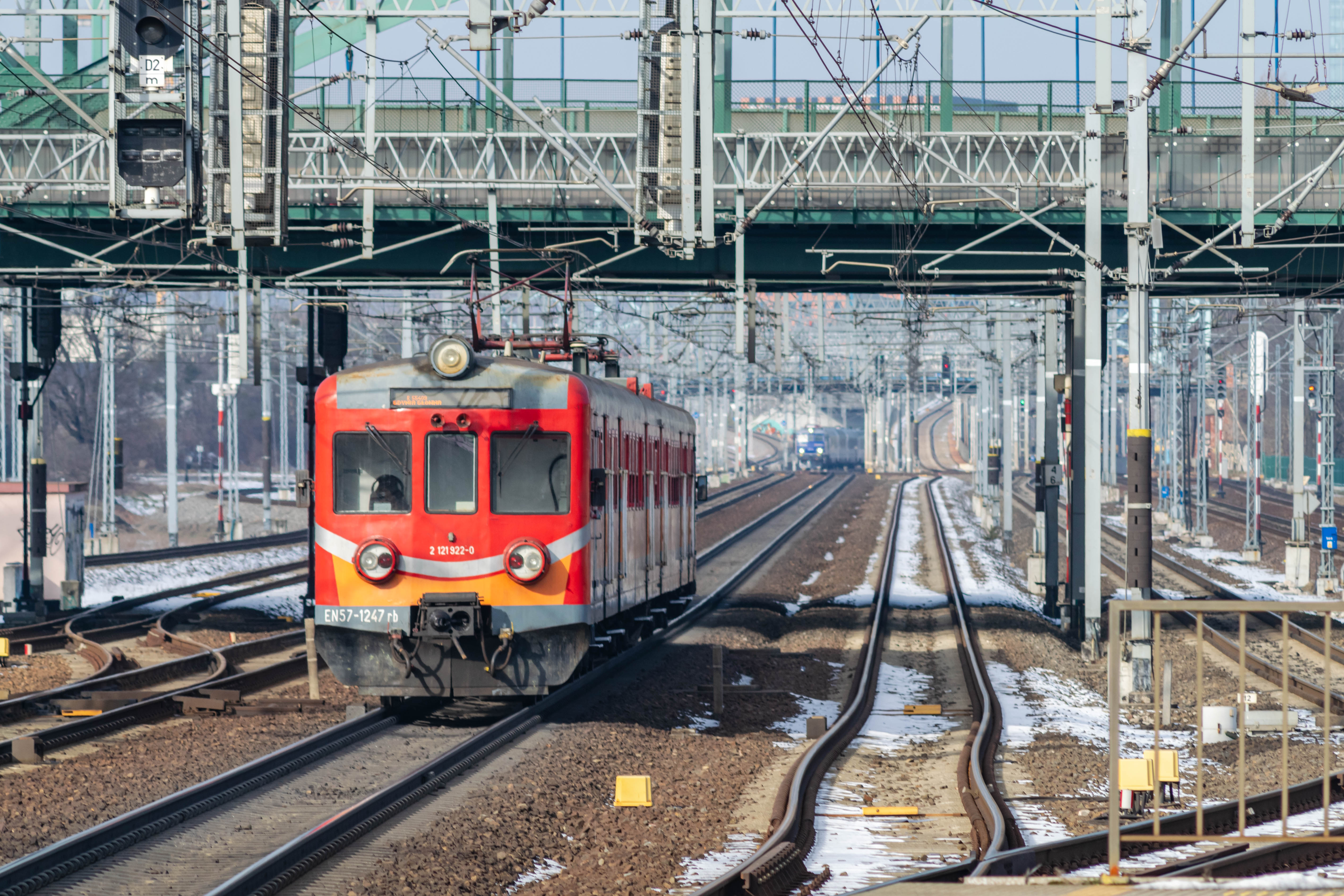 red-silver-orange train leaving the station with blue locomotive visible in background
