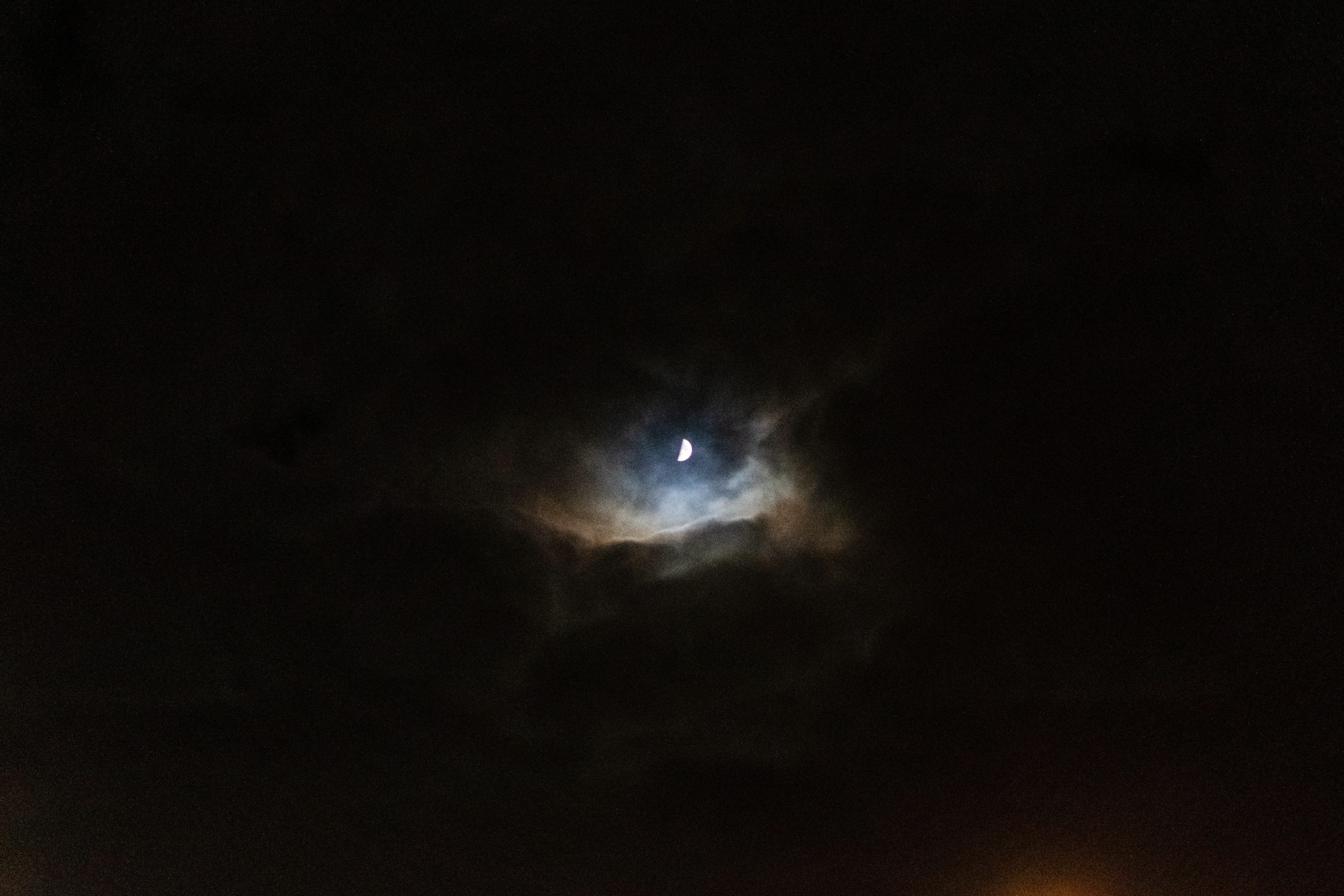 moon visible through clouds that are illuminated by it