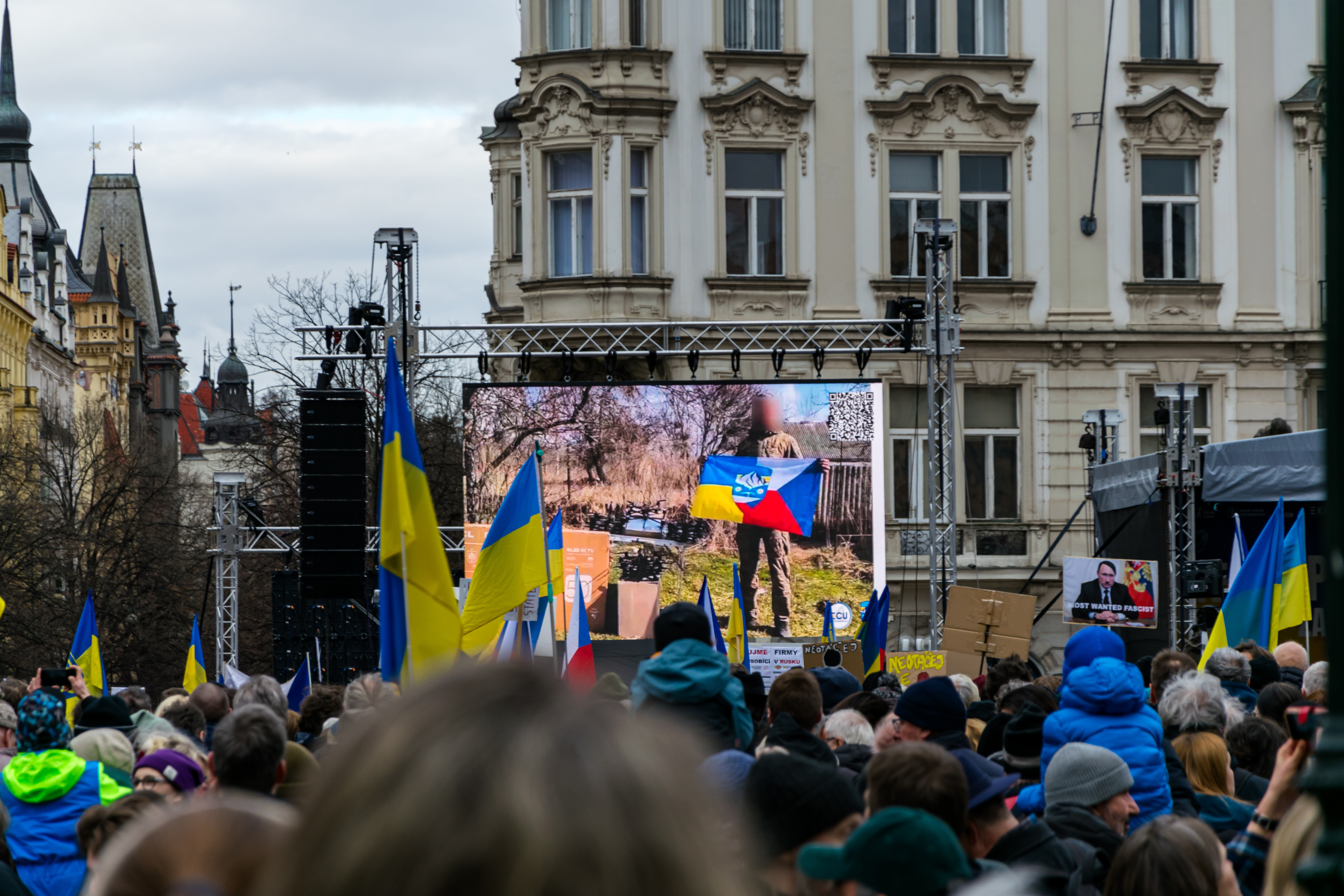 Closeup of a screen showing a guy with blurred face holding a flag that looks like a merged Czech and Ukrainian flag