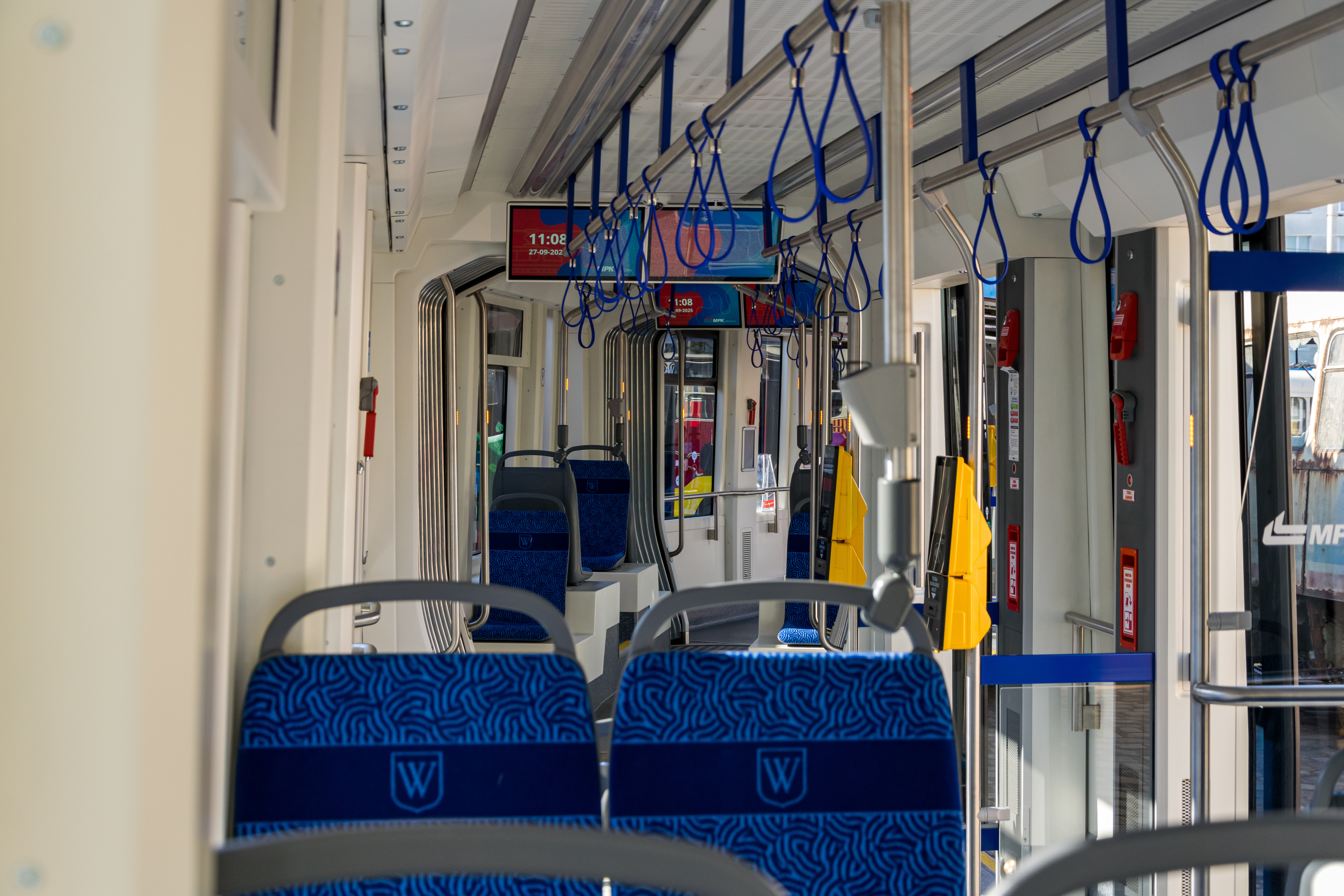 Interior of PESA 146N, with blue seats, metallic handrails and wide information displays